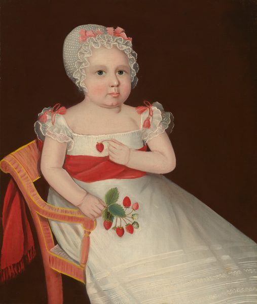 A young, pale-skinned girl sits on a wooden chair in this vertical portrait painting. Her body is angled to our right so her feet are cut off by the bottom right corner of the canvas. She has round cheeks, green eyes, a dainty mouth, and a cleft chin. A ruffled white bonnet tied around the crown with a carnation-pink bow covers her hair. Her white dress has short, flutter sleeves, a straight neckline across the chest, and a high waist. The gossamer-white skirt falls to her feet and has decorative bands near the hem. A cherry-red sash is tied around her waist and falls over the back of the chair. The girl holds a bunch of red strawberries in one hand and holds one up by her chest with the other. The background is dark bronze brown.