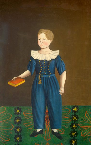 The image shows a full-body portrait of a young child standing upright. The child has short light brown hair and is looking slightly to the side with a neutral expression and rosy cheeks. The child is wearing a blue outfit with decorative gold buttons down the front, a large white ruffled collar, and matching gold tassel detail on the waist. In their right hand, they hold a red book with a yellow edge. Their black shoes are visible, positioned on a decorative floor that features a floral pattern with green and black geometric shapes and yellow floral accents. The background is a plain brown.