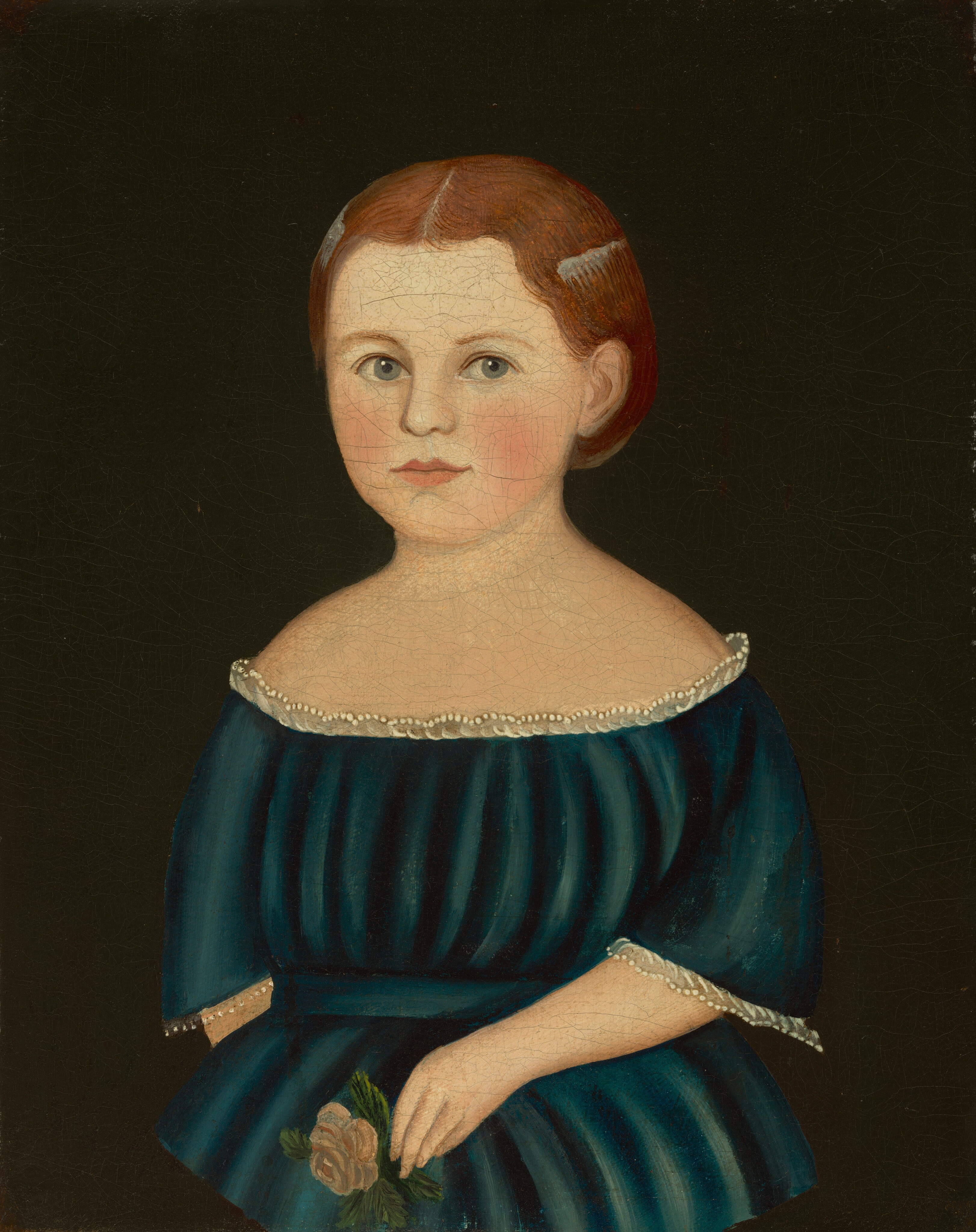 The image shows the upper half of a young girl, seated with her torso facing the viewer. She has fair skin, light blue eyes, thin eyebrows, and slightly rosy cheeks. Her reddish-brown hair is styled neatly with a middle part, and she is wearing a dark blue off-the-shoulder dress with decorative trim. She is holding a small flower with green leaves in her hand. The background is a solid dark color.