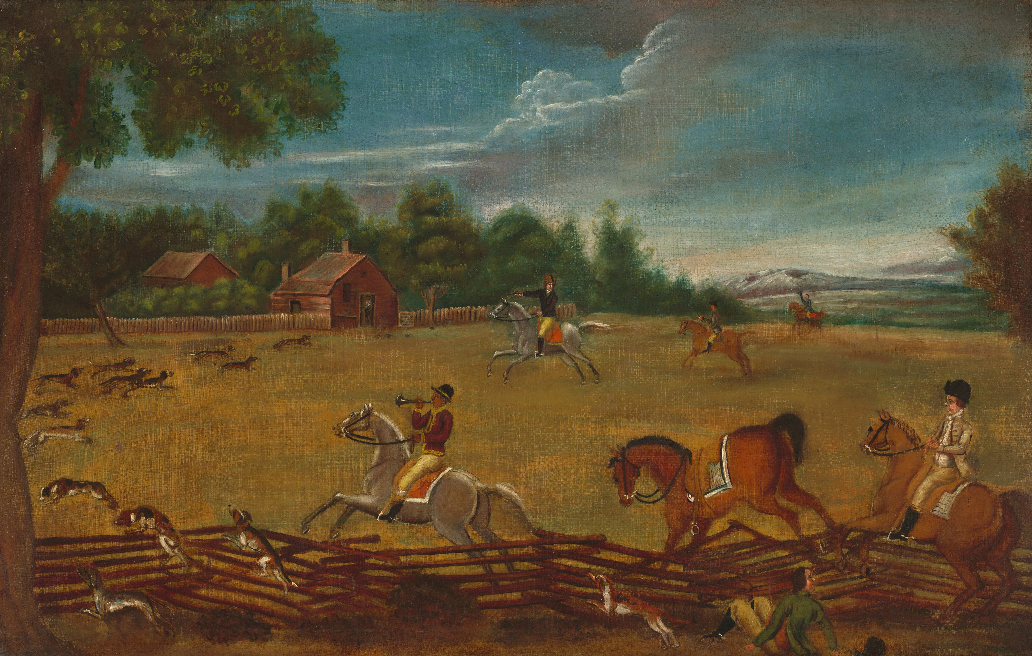 The painting depicts an outdoor equestrian scene featuring riders on horseback. Closest to us is a low fence of thin wooden logs. Three riders on horseback are jumping over the fence, as are a line of dogs. One of the riders is blowing a horn, and another seems to have fallen off his horse and is sitting on the ground near the bottom right corner. Beyond the fence is a yellow field, and at the edge of the field are two red buildings that more dogs and riders are heading towards. Surrounding the buildings are green trees, and in the background on the right are distant hills painted in grays and browns. The sky above shows blue tones with fluffy white clouds.