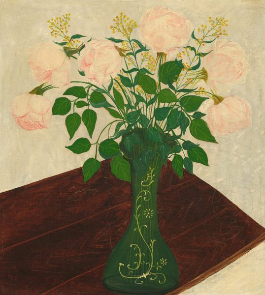 In this painting, a bouquet of large, pale pink roses fills a green vase decorated with yellow floral patterns, which is resting on a wooden table with a rich, dark brown surface. Flowers extend outward from the center to fill much of the upper portion of the image, while the wooden surface stretches diagonally from the bottom left corner to the center. The pink roses are surrounded by green leaves and smaller groups of yellow flowers. The wall behind the flowers is a pale gray color.