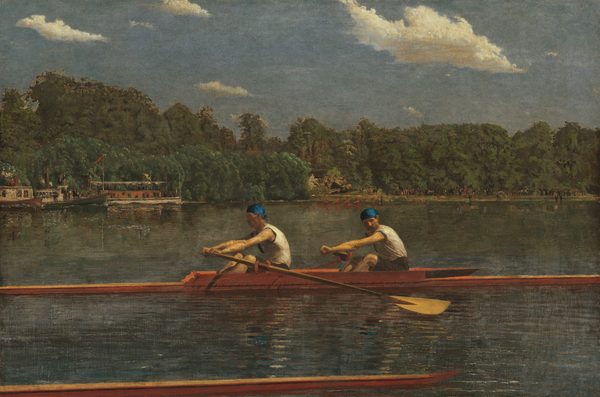 Two men with pale skin, wearing white sleeveless shirts and royal-blue caps, row in unison in a long, narrow boat on a placid blue river in this horizontal landscape painting. The low, honey-colored wooden boat extends off both sides of the canvas. Both men face our left as they row to our right. The man in front looks ahead of him, beyond the stern of the boat, and the man to our right, closer to the bow, tucks his chin down to look past his shoulder. Their bare, muscled arms are extended straight as the two oars sweep back. The tip of another boat runs close and parallel to the bottom edge of the composition, spanning the left three-quarters of the painting. The opposite riverbank is lined with a dense forest of pine-green trees. People crowd along the decks of a steamboat and a paddleboat near the riverbank to our left. Another narrow skuller, rowed by four people wearing ruby-red shirts, cuts through the water at the back center of the river. The riverbank beyond is lined with people, painted with strokes of black and white, and minuscule touches of red. The horizon comes halfway up the composition. Cream-white clouds float across a muted, topaz-blue sky above the trees.