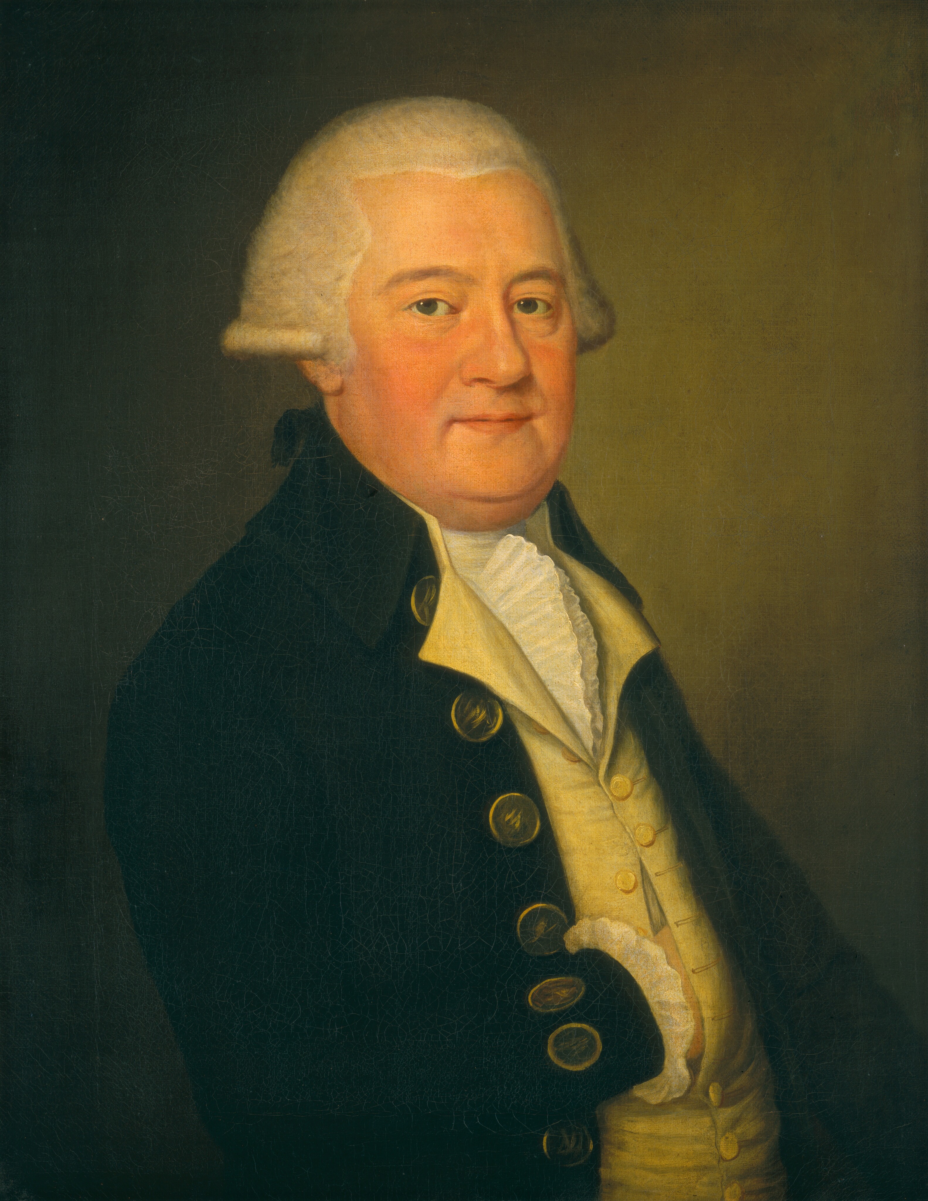 The image depicts a man in a three-quarter view portrait. He is looking at the viewer, showing his face and upper body. The man has a round face with gentle features, fair skin, and white hair styled in 18th-century fashion. He is wearing a dark coat with gold buttons, a light waistcoat, and a white cravat with ruffled edges. The background is plain and dark.