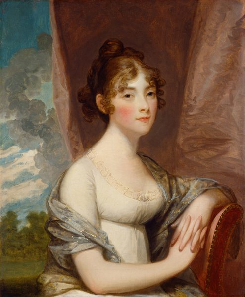 Shown from the hips up, a young woman with pale skin, pink cheeks, and copper-red hair sits gazing at us in this vertical portrait painting. She has wide-set, brown eyes, a pointed chin, and her pink lips are closed with a mere hint of a smile. Curls frame her forehead and face, and the rest of her hair is pulled up at the back of her head. She sits on a chair upholstered dusky rose-pink chair with her body angled to our right. Her left arm, on our right, rests on the curved back of the chair, and her fingers are interlaced. Her white gown has a low, scooped neckline trimmed with ruffles and is tightly cinched under her bosom. A dove-gray shawl with gleaming straw-yellow accents wraps around her back and drapes loosely over her shoulders and upper arms. A rust-red cloth hangs in folds from the top edge of the painting to fill the right three-quarters of the background. It is pulled aside to the left to reveal a glimpse of a landscape with a green lawn and trees under an azure-blue streaked with white and gray clouds.