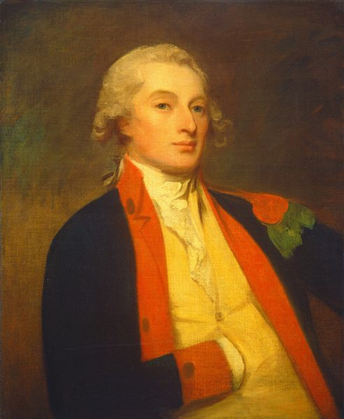 The image shows a painting of the upper half of a man's body. The man is positioned in a three-quarter view, slightly turned to his right. He has a fair complexion with light, curly hair. His facial features include a smooth complexion, blue eyes, and a straight nose. The man is dressed in an 18th-century military uniform with a high-collared, dark blue coat with red facings and gold trim. He wears a pale yellow waistcoat and a white shirt with a frill. There is no visible jewelry or objects in his hands. The background is a dark canvas.