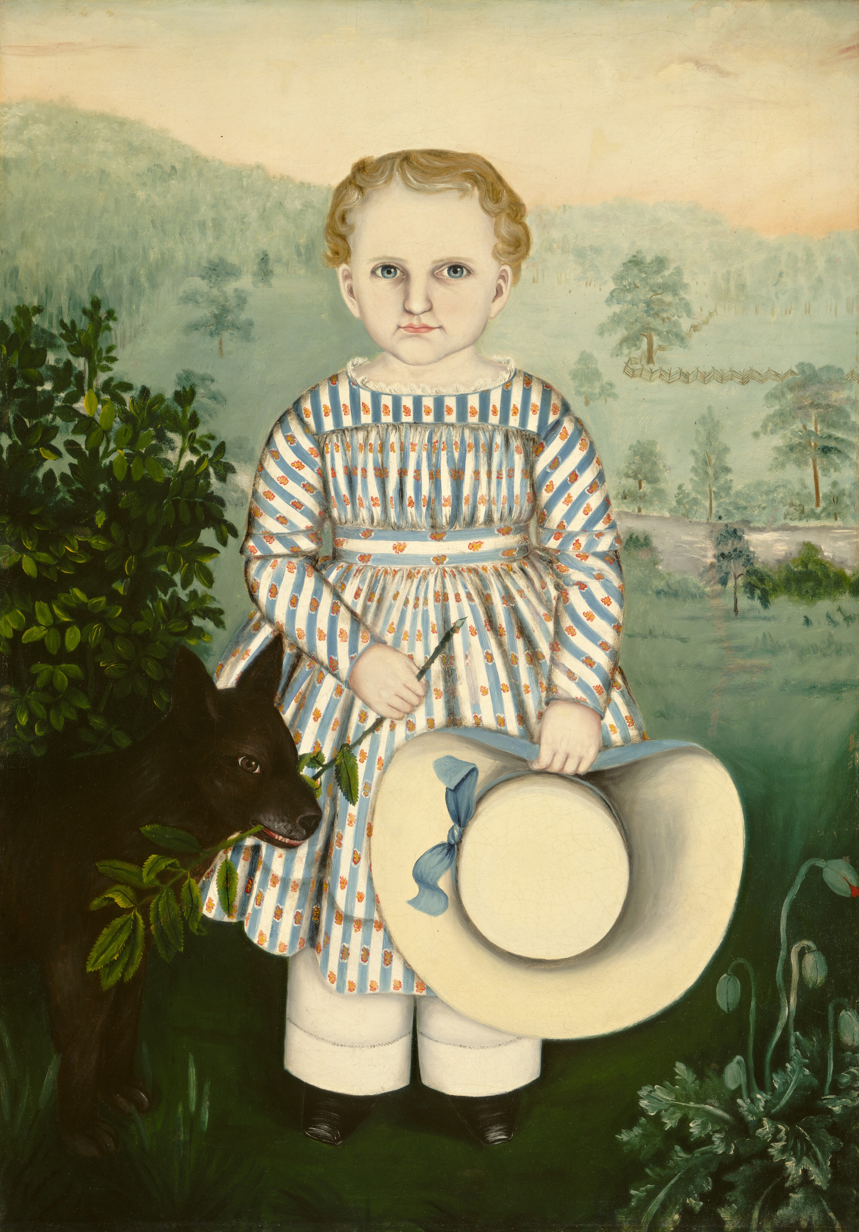 The image shows a child standing with both hands in front. The child has a full face, large, round eyes, and fair, short, curly hair. They are wearing a dress with blue and orange stripes and small floral patterns, white pants, and black shoes. The child holds a thin stick in one hand and a wide-brimmed straw hat with a blue bow in the other. A small black dog stands at the child's left side, appearing to sniff a leafy branch. The background features soft green hills, scattered trees, and a light sky.