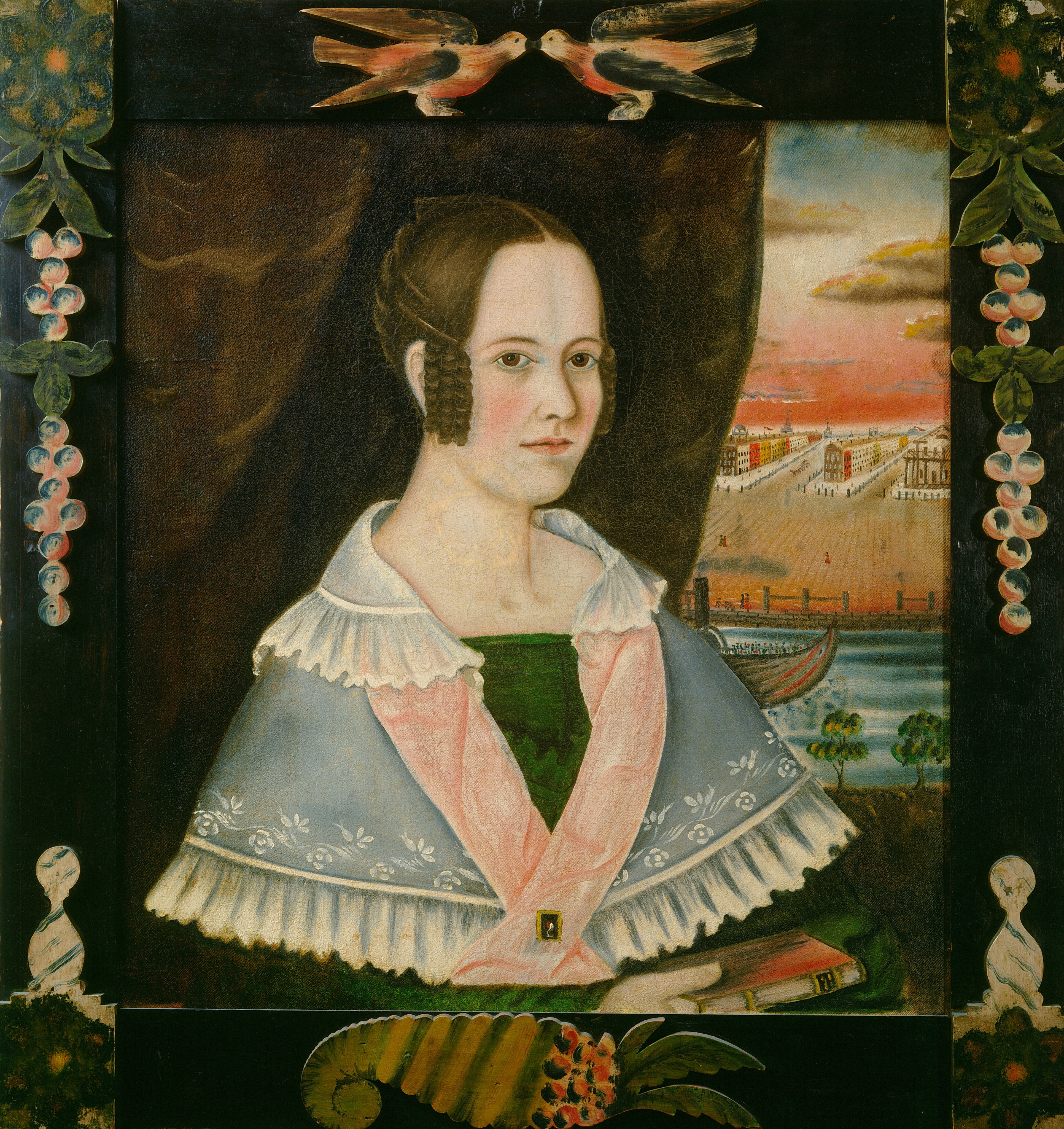 The image shows a woman's upper body, facing forward with her head slightly turned to the left. She has soft facial features, light skin, and dark brown ringlet hair styled around her face. She wears a dress with a white lace collar, a pastel blue shawl with white floral patterns, a pink bow around her neck, and a small brooch. She holds a book in her left hand. The background includes a dark curtain on her right and a scenic view on her left with a river, buildings, a boat, and a colorful sky. The portrait is framed with floral and bird motifs.