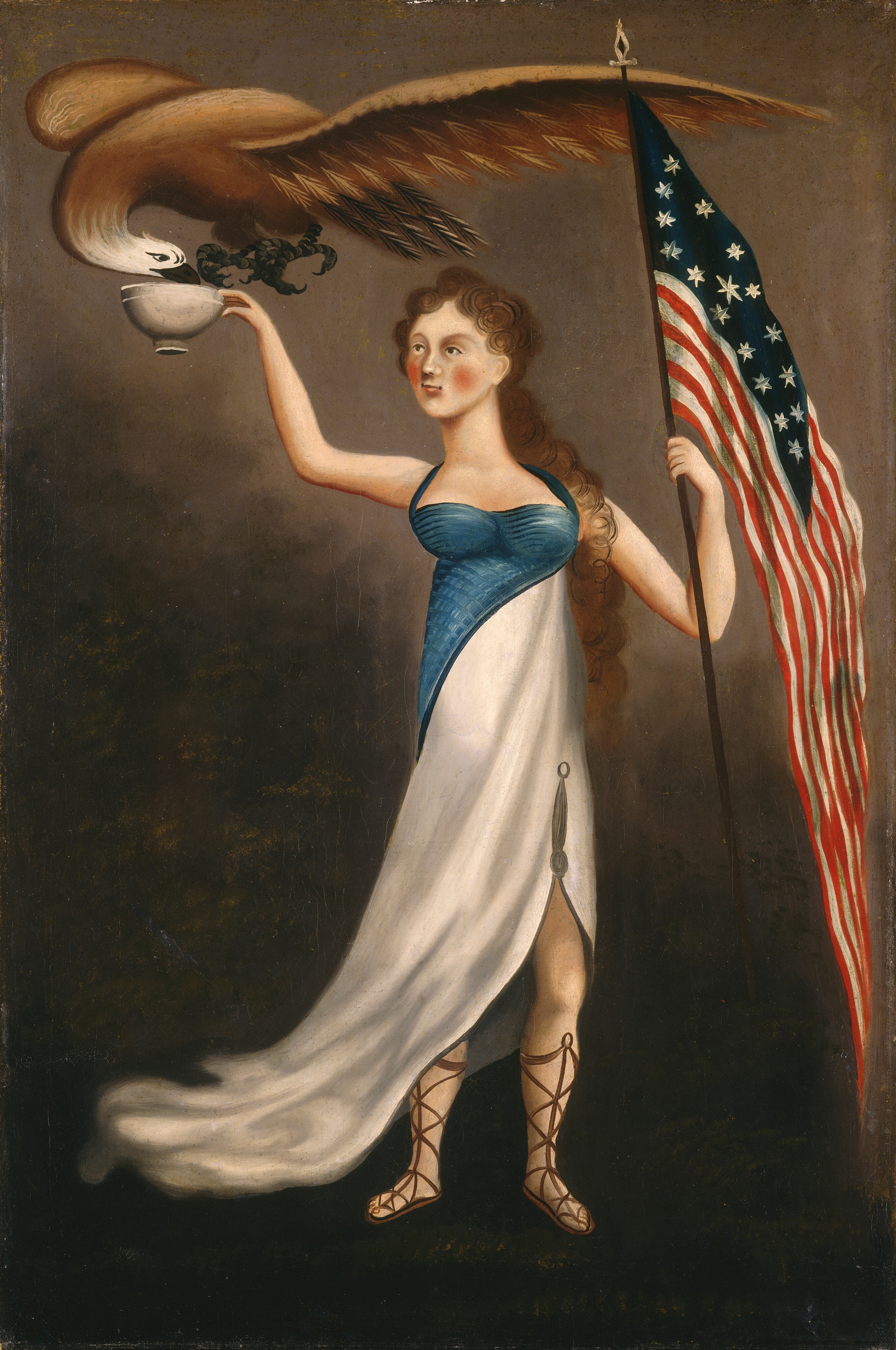 This painting shows a woman standing upright, holding a cup with a bald eagle drinking from it. She has fair skin, rosy cheeks, red lips, long curly brown hair, and is wearing a classical style gown. The gown has a blue bodice that cuts diagonally across her torso, under which is a flowing white skirt gathered at the side to reveal her leg and the lace-up sandals she wears. She holds a thin pole with an American flag hanging from it. In her other hand, she holds a white cup or bowl. A large bald eagle flies over her and dips its head down to drink from the cup. The background is brown, and it is lighter at the top of the image and darker at the bottom.