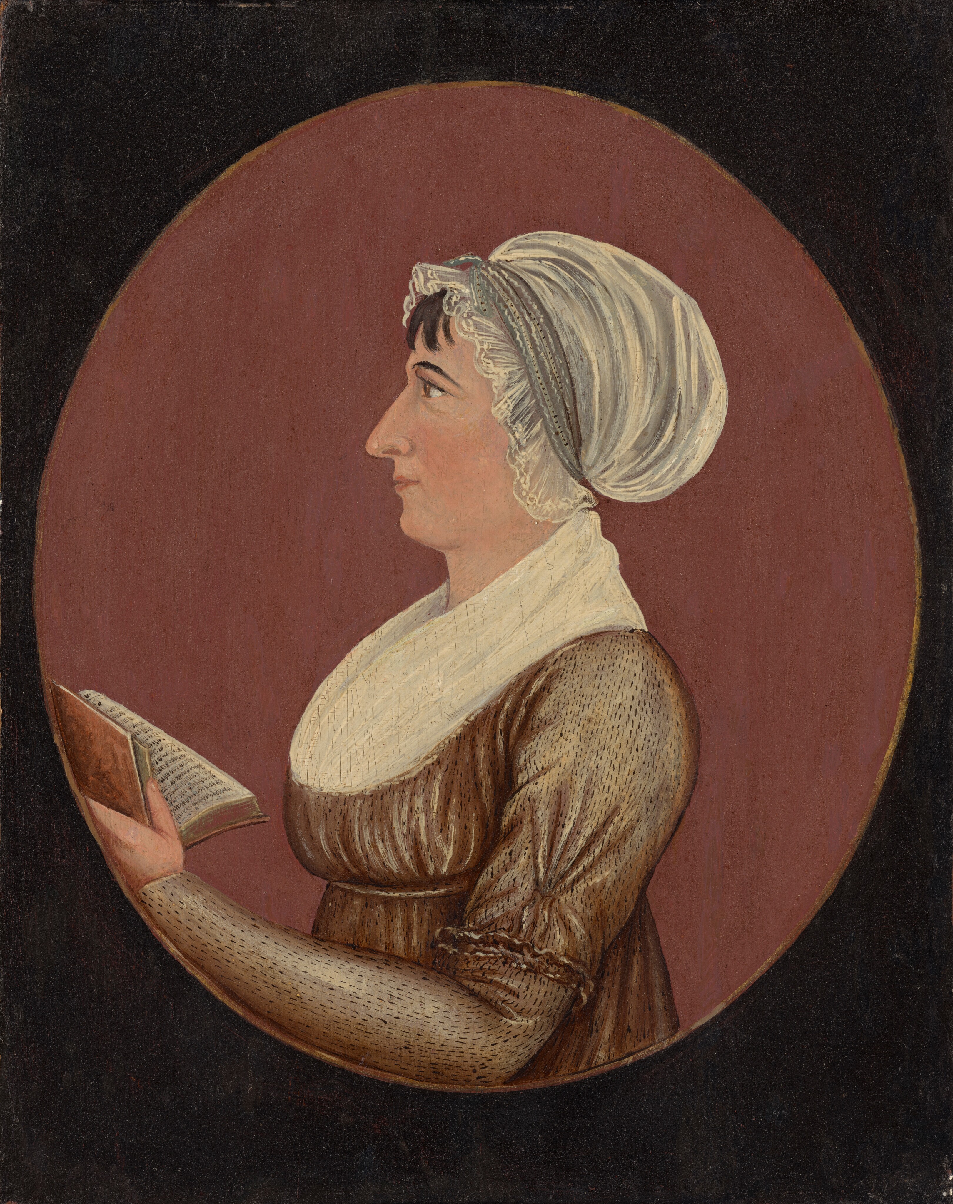 The image shows a woman in profile from the waist up. She has distinct facial features, dark hair with a white bonnet, and is wearing a brown dress with a white fichu. She is holding an open book in her left hand. The background is a plain, muted red oval area within a darker rectangle.
