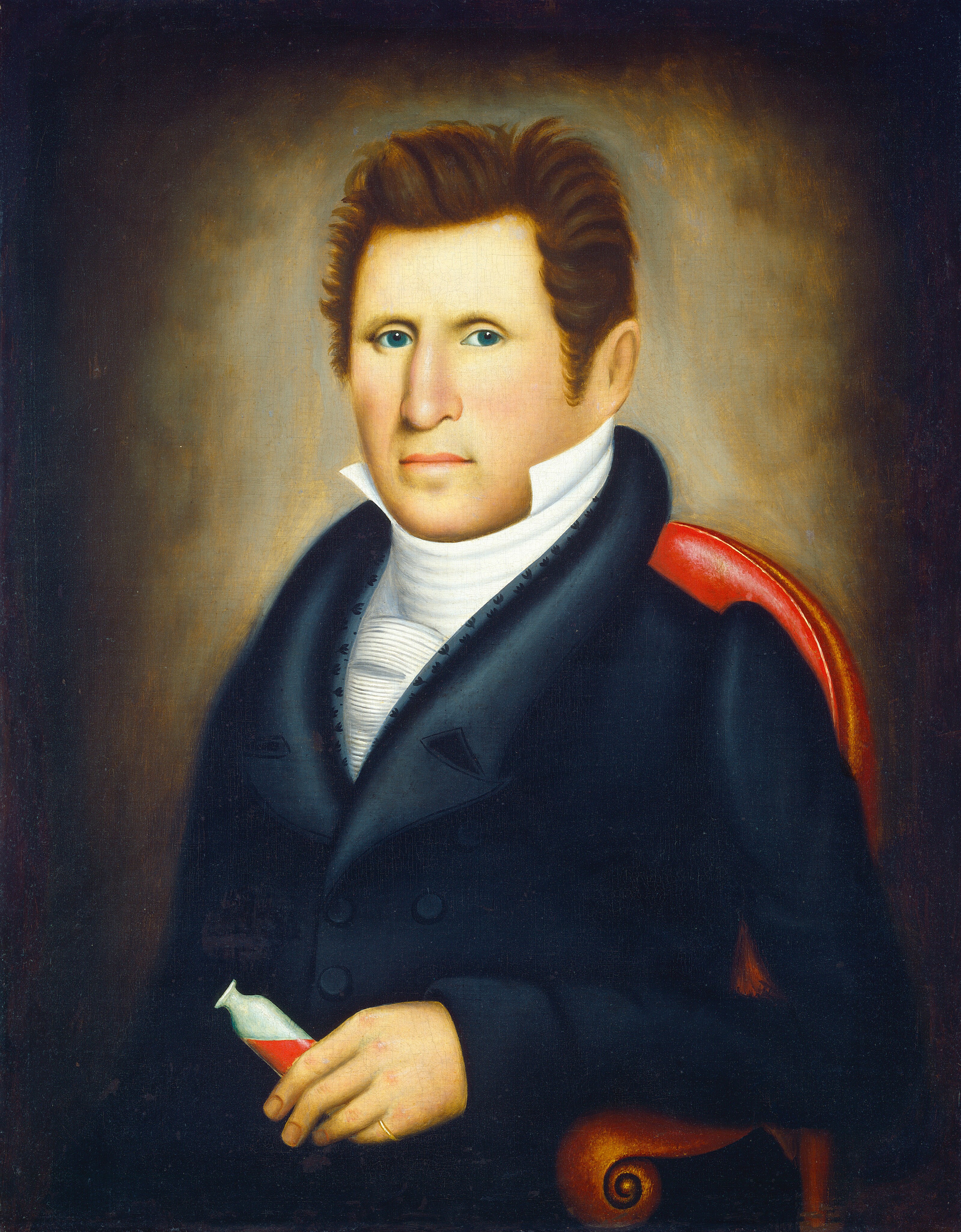 This image depicts the upper half of a man's body. He is seated and facing forward with his body slightly angled to the right. The man has light skin, blue eyes, and light brown, upward-styled hair. His facial features are well-defined, and he looks directly at the viewer with a faintly serious expression. He is dressed in formal attire, with a dark coat over a high-collared white shirt with horizontal pleats and a cravat-like neckwear. His left hand holds a small vial containing a red liquid, and a wedding band is visible on his right ring finger. The chair has red upholstery with a decorative scroll design on the armrest. The background is a dark brown color that lightens around the figure, drawing attention to him.