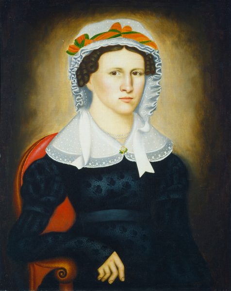 The image depicts a woman seated in a red chair. She is facing the viewer, with distinct facial features, fair complexion, dark hair styled in curls, and wearing a white bonnet with a green and orange ribbon. She has a dark, patterned dress with long sleeves, a white lace collar, pearls around her neck, and a circular brooch at the center of her collar. The background is a gradient from dark to light hues.