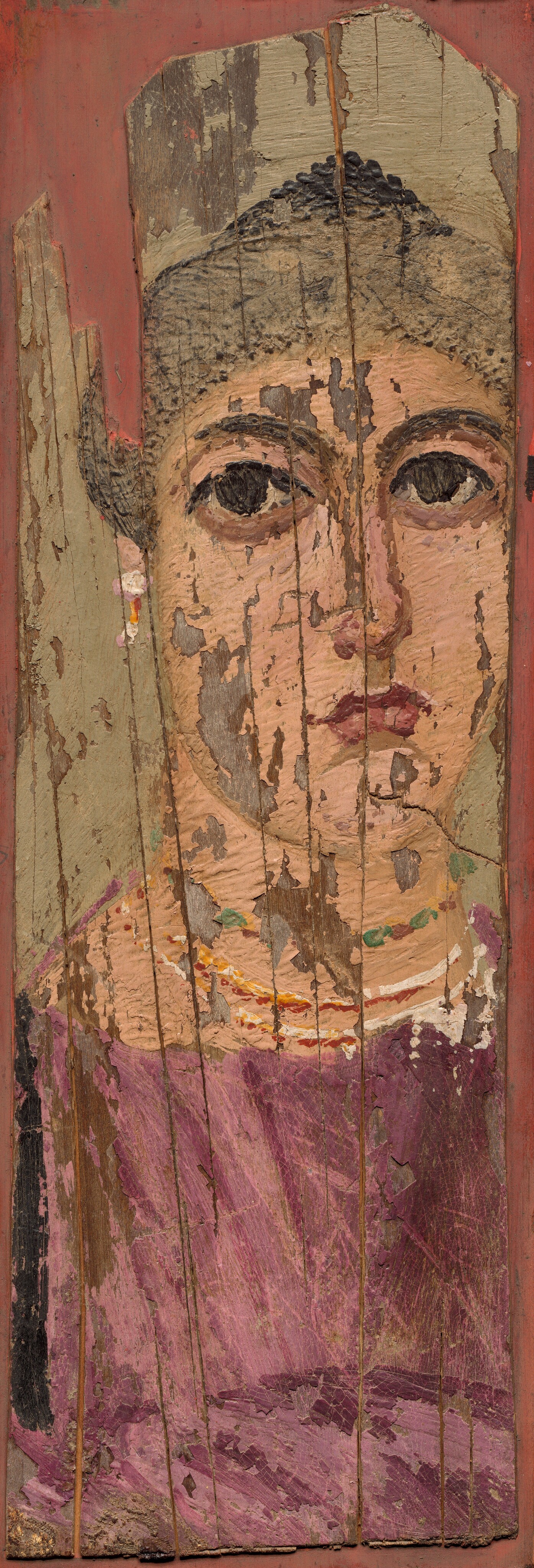 This painting shows the upper body of a person, focusing on their face and shoulders. The person is facing forward, looking directly at us. Their facial features include pale skin, large dark eyes, defined eyebrows, a straight nose, and a closed mouth with full, red lips. Their dark hair is styled on top of their head. The person is wearing a garment in shades of purple, with visible gold and white bands. Earrings with small dots of red and white hang from the ears. The painting is aged, with noticeable signs of wear and peeling occurring from the wood it was painted on, creating vertical lines and patches where the paint is no longer present.
