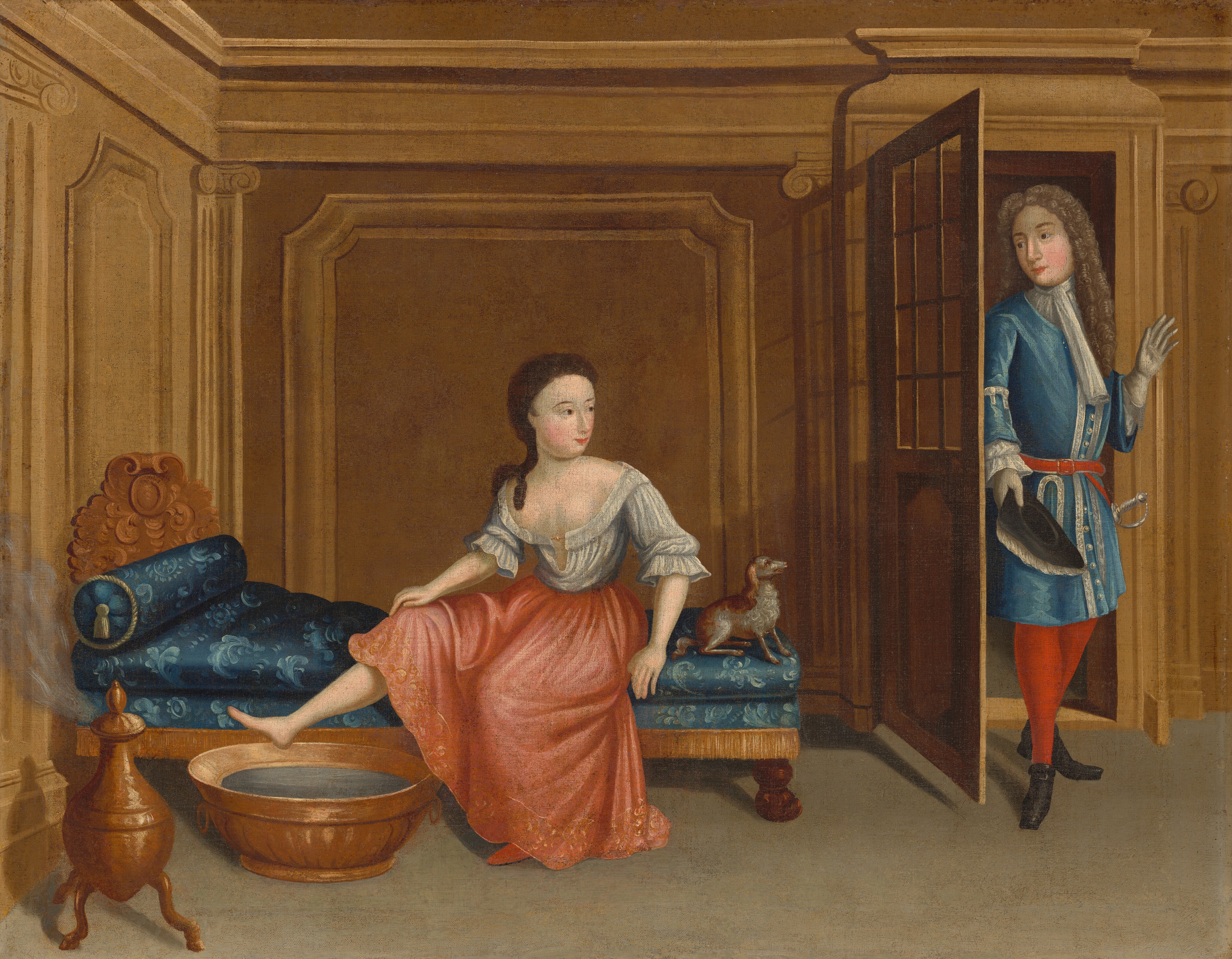 The painting shows a woman and a man in a wood-paneled room. The woman is on the left, seated on a blue chaise lounge with carved wooden details. She is wearing a white blouse and a pink skirt, with one foot hovering above a basin of water. Her head is turned to the right. A small gray-and-brown dog is on the end of the chaise longue next to her. On the right, the man is entering the room, the pushing the wooden door open. He is holding a hat and is dressed in a blue tunic with white details, gray gloves, a red belt and red tights, and black shoes. They both have pale skin with rosy cheeks and red lips, and the woman has brown hair pulled back at the nape of her neck while the man has long gray curls. They are in a room with wood paneled walls and what looks like a heater on the far-left emitting steam.