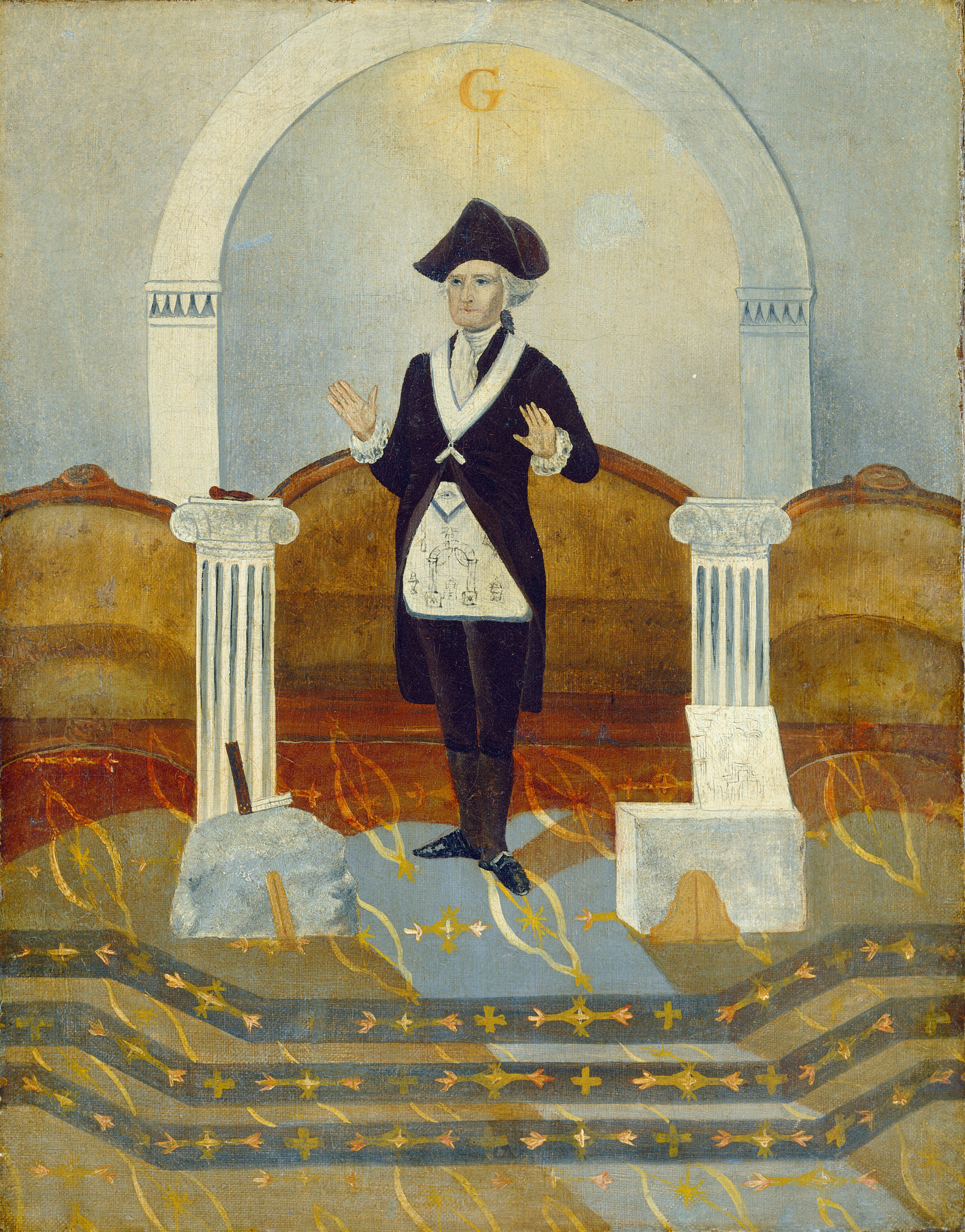 The image shows a man standing at the center. He is facing forward with his hands slightly raised at his sides. He has a serious expression and wears a tricorne hat. His hair is white or gray, styled beneath the hat. The man wears dark formal attire with a white collared shirt visible beneath, and a white apron with symbols. To his right, a column supports an object, and on his left, there's another column, a stone with a tool, and a small structure resembling a seat. The background has an archway with the letter 'G' displayed, and a patterned floor with golden and black designs. Surrounding the figure are brown and red tones.