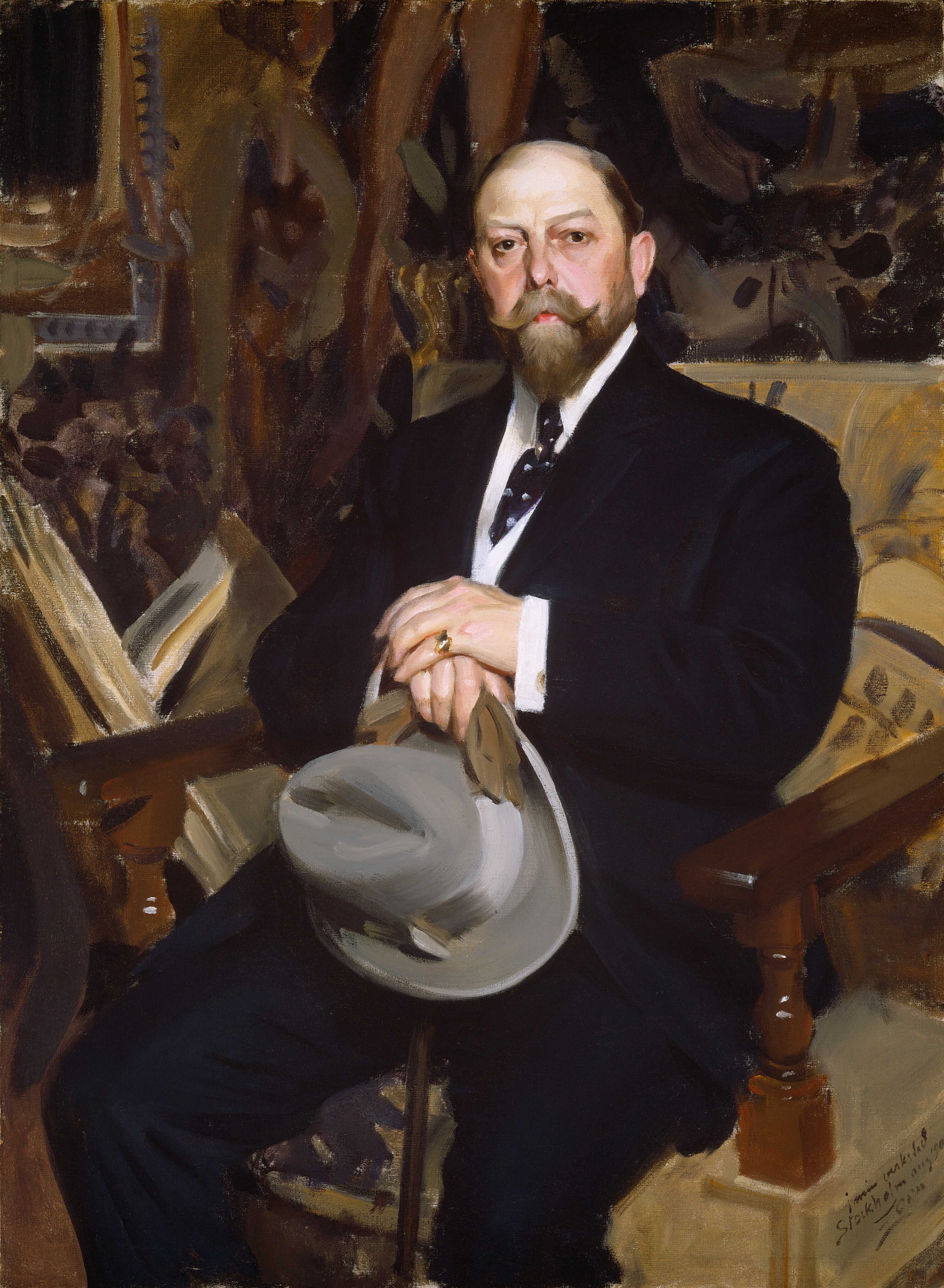 This painting shows a portrait of a middle-aged man who looks out at us. He is seated in a chair, turned slightly to the left, with his hands holding a gray hat in his lap. The man has pale skin with a brown mustache and a neatly trimmed beard, and his hair is slicked back and appears to be balding. He is wearing a dark suit with a white shirt and a patterned tie. On one of his fingers, he wears a gold ring. The background of the painting is an ornate interior, with richly patterned wallpaper, drapery, or furniture suggested by thick brushstrokes in shades of brown, tan, and black.