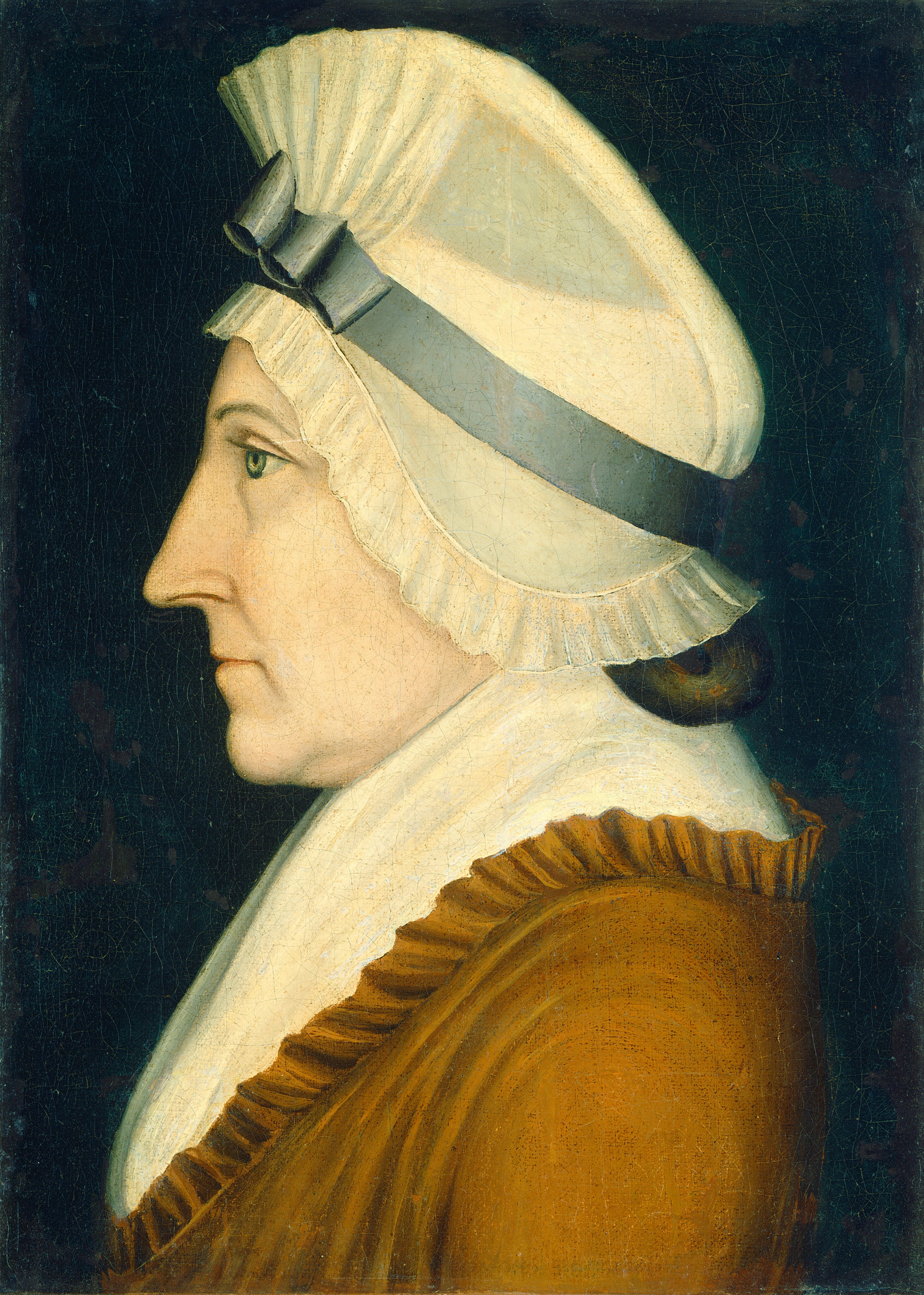 The image shows the profile of a person from the chest up, positioned in a side view orientation facing left. The person has a prominent straight nose, deep-set eyes, and distinct eyebrows. Their hair is covered by a large white cap with pleats and a blue-gray ribbon. They are wearing a brown garment with a high, white pleated collar. The background is a dark, solid color.