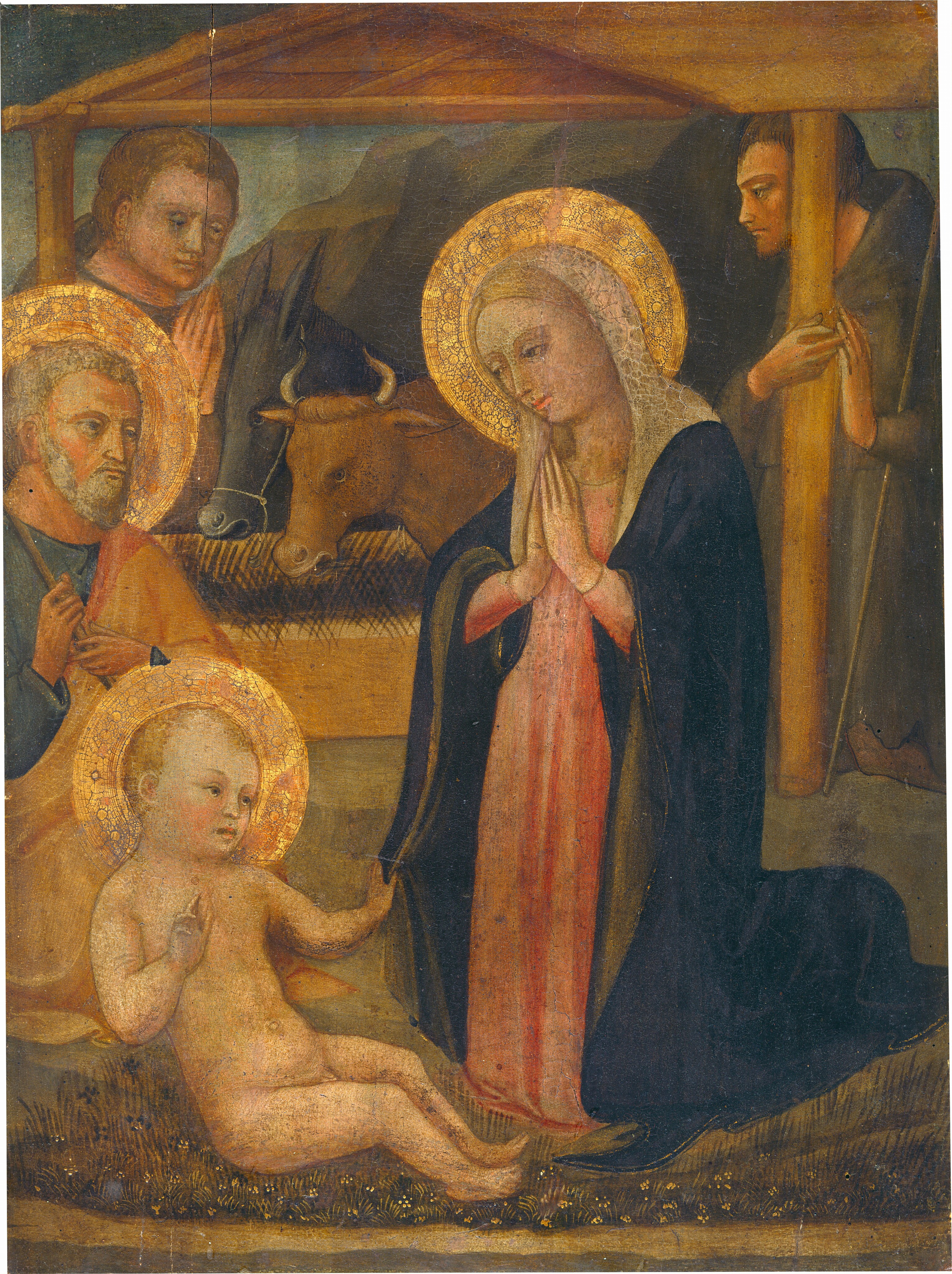 A woman kneels and gazes at a nude baby boy half-sitting on the ground to the left in this vertical painting. A man with a gray beard and hair kneels to the left, and all three people have gold halos. Two more people wearing brown robes are under a wooden structure over a trough in the background. All the people have pale skin with rosy cheeks. Just to the right of center, the woman’s blond hair is covered by a light brown and blush-pink veil, and she bows her head to look at the boy with her hands pressed together at her chest. A marine-blue mantle is draped over her coral-pink robe. The nude child faces the woman and reaches his far hand to grasp the edge of her mantle. He leans back slightly, as if supported against the knees of the man behind him. The older man faces our right and wears a saffron-orange mantle draped over his spruce-blue robe. The wooden staff he holds with both hands rests against his near shoulder. The staff is cut off by the left edge of the composition. The ground beneath the child and woman is carpeted with dark green grasses and tiny tan, white, and dark blue flowers. The structure behind the trio has a shallowly pitched flat roof held up by slender beams. An ox and donkey eat at a wooden trough inside and are flanked by two pale-skinned men in robes. The man on the left has dark blond hair and the other has brown hair and rests a staff in the crook of one elbow. A tall, rocky mountain and muted blue-green sky fill the background.