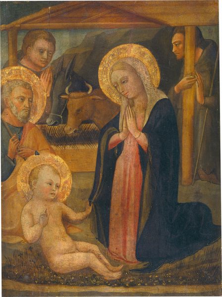 A woman kneels and gazes at a nude baby boy half-sitting on the ground to the left in this vertical painting. A man with a gray beard and hair kneels to the left, and all three people have gold halos. Two more people wearing brown robes are under a wooden structure over a trough in the background. All the people have pale skin with rosy cheeks. Just to the right of center, the woman’s blond hair is covered by a light brown and blush-pink veil, and she bows her head to look at the boy with her hands pressed together at her chest. A marine-blue mantle is draped over her coral-pink robe. The nude child faces the woman and reaches his far hand to grasp the edge of her mantle. He leans back slightly, as if supported against the knees of the man behind him. The older man faces our right and wears a saffron-orange mantle draped over his spruce-blue robe. The wooden staff he holds with both hands rests against his near shoulder. The staff is cut off by the left edge of the composition. The ground beneath the child and woman is carpeted with dark green grasses and tiny tan, white, and dark blue flowers. The structure behind the trio has a shallowly pitched flat roof held up by slender beams. An ox and donkey eat at a wooden trough inside and are flanked by two pale-skinned men in robes. The man on the left has dark blond hair and the other has brown hair and rests a staff in the crook of one elbow. A tall, rocky mountain and muted blue-green sky fill the background.