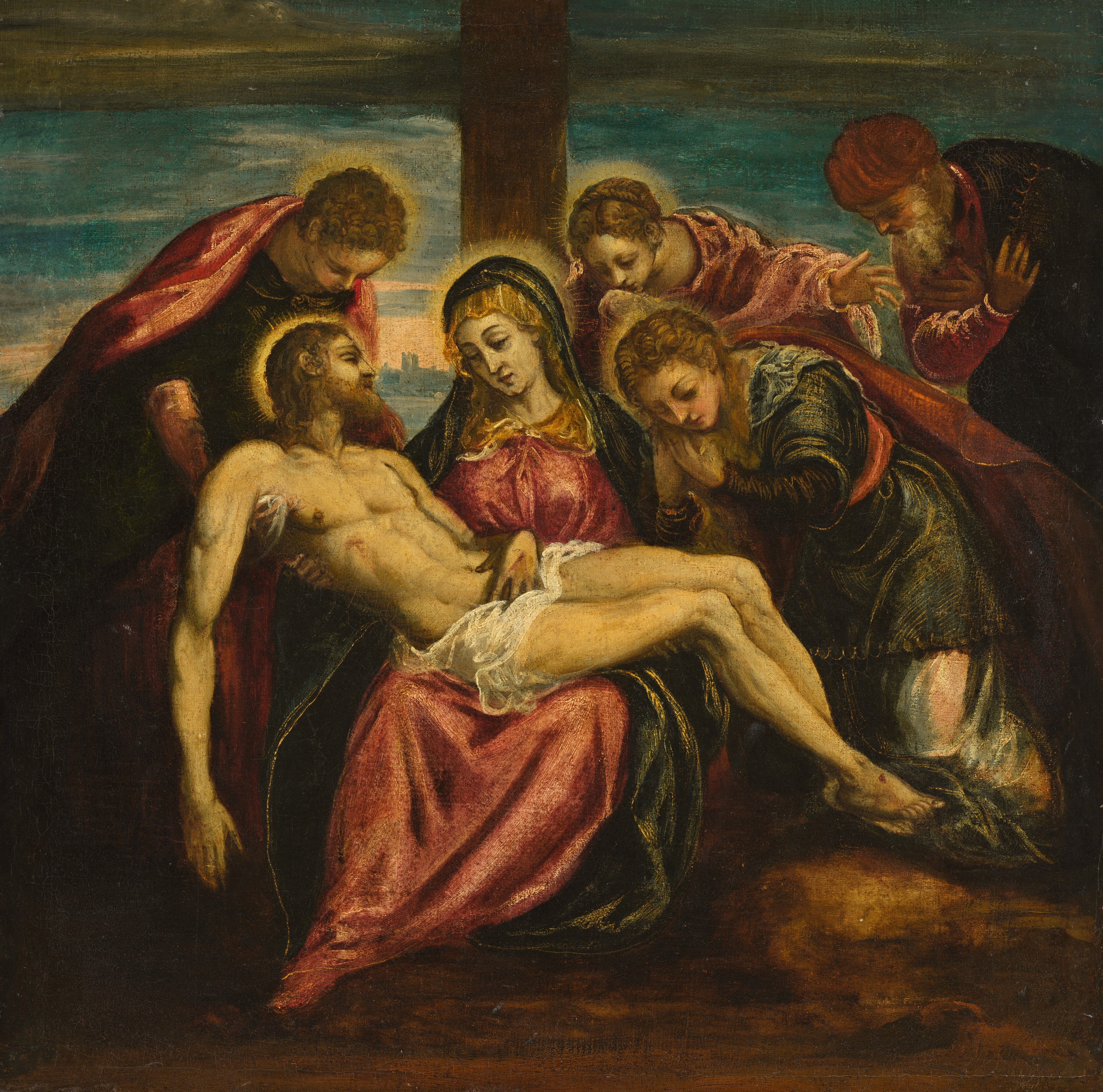 A nearly nude man, Jesus, lies across the lap of one woman as four more people bow and crouch to be close to him in this square painting. The people all have pale skin with a yellow cast. Five of the six people have blond hair and halos. The woman, Mary, sits at the foot of a vertical wooden beam. She wears a gold-colored veil over her head and shoulders. A gold-trimmed, midnight-blue mantle drapes over her head and over her raspberry-pink dress. She braces Jesus’s nearly nude, muscular body with one hand under his upper back to the left and his knees to the right. Jesus’s eyes are closed, and his limbs hang limp. He has a blond beard and hair, and a white cloth is wrapped around his hips. Red streaks mark the back of his hands and the foot we can see, and a gash is over his right ribs. To the left, a clean-shaven man supports Jesus’s torso with hands hooked under the dead man’s armpits. Two more women bend over Jesus’s body to our right of Mary. They also wear midnight blue and pink, and both hold their hands by their faces. The only person without a halo is to the right, near the edge of the canvas. He has a long white beard and wears a pink turban and robe under a dark cloak. He crosses both hands over his chest as he leans forward toward Jesus. A dark tan-brown streak crosses the muted blue sky above. A few buildings are silhouetted against peach-toned light along the horizon, which comes about halfway up this composition. The ground beneath the group is earth brown.