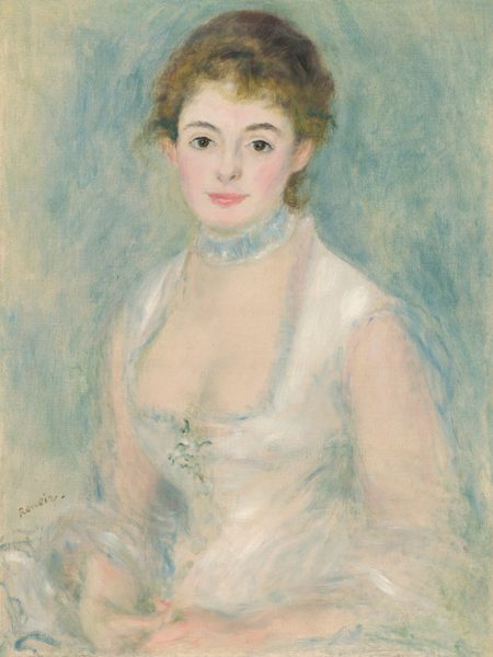 Shown from the hips up, a pale-skinned young woman wearing a white dress sits smiling gently at us in this vertical portrait painting. Blended strokes of pearl white, cool green, and muted blue create an overall soft, almost blurred look. The woman’s body is angled to our left, but she turns her face to look at us with brown eyes under dark, curved brows. She has a heart-shaped face with rosy cheeks, a thin, short nose, and full, pink lips, which are closed in a smile. Her honey-blond hair is swept up and back, but a few tendrils curl on her forehead and the nape of her neck. The neckline of her sleeveless white dress is cut low. The bodice fits tightly to a narrow waist, and a sprig of flowers is suggested by a few strokes of fern green and bright white at the center of the chest. A pale blue collar or ruffled band encircles her neck like a choker. Her hands rest together in her lap, and a white cloth loops over her forearms. The background is painted with loose strokes of powder blue and sage green against the off-white of the canvas, which is visible in some areas, especially along the left edge. The artist signed the painting near the woman’s elbow to our left, “Renoir.”