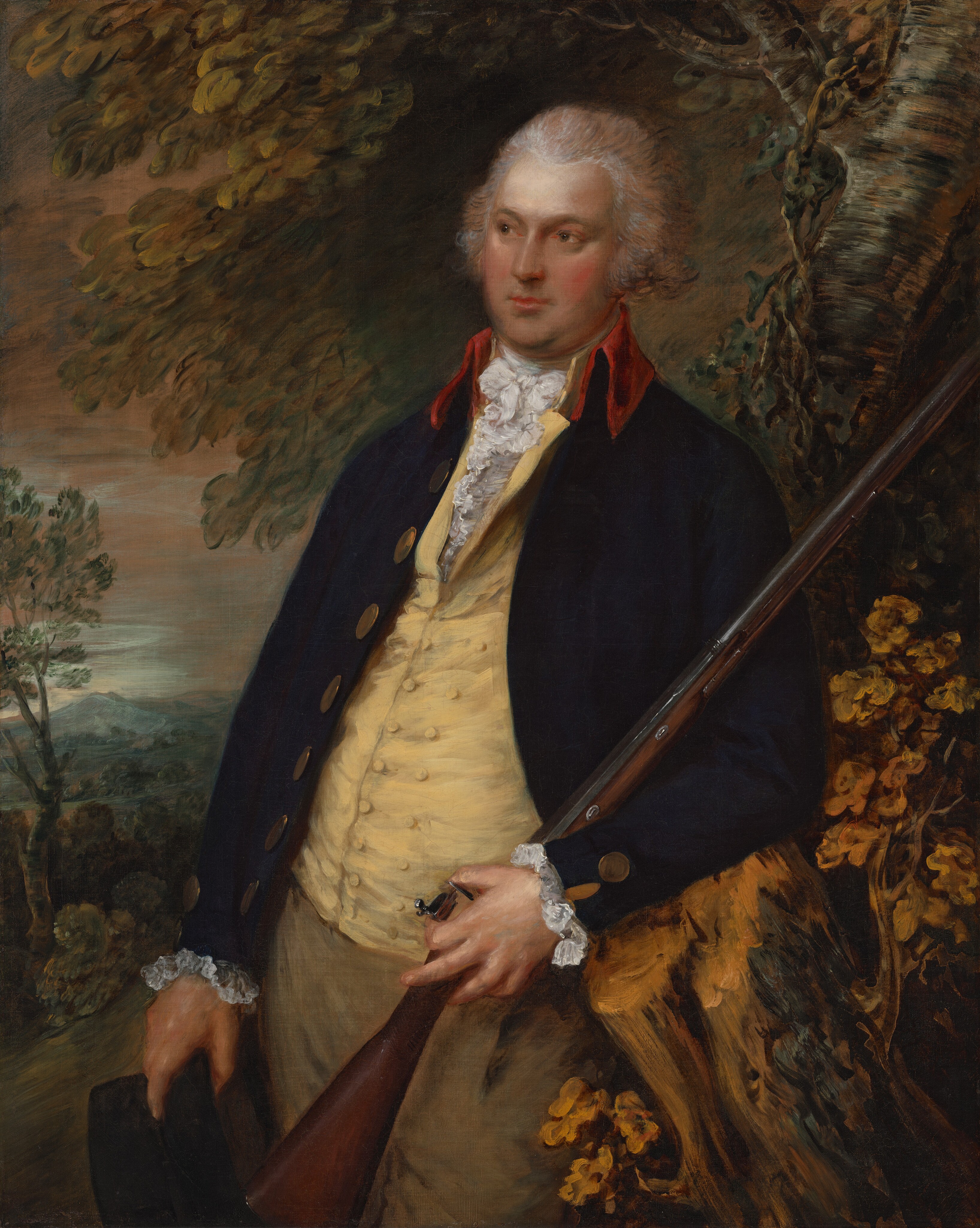 The image shows a man in a portrait from the waist up. He has fair skin, curly light-colored hair, and wears a dark navy coat with gold buttons and a vibrant red collar. Under the coat, he wears a pale yellow waistcoat with a high, ruffled white shirt collar. The man's hands are visible, with one on a long rifle held upright and the other on the brim of a black hat at his side. The background features green foliage, distant mountains, and a serene sky.