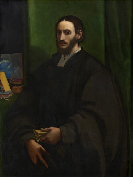 A bearded, pale-skinned man with shoulder-length, dark brown hair is shown from the hips up against a dark, emerald-green curtain in this vertical portrait painting. The man’s body is angled slightly to our left, while his head turns to look directly at us with dark, shadowed eyes. His chin-length hair is parted down the middle and tucked behind his ears. He wears a dark robe over a white shirt with a high collar. In his left hand, to our right, he holds a folded piece of yellowish paper or cloth, and his other hand rests just below it with fingers pointing downward. He is lit from our right so the far side of his face is thrown into shadow. At his shoulder and to our left, a shelf or table covered with green holds a globe, an open book with pages filled with text, a stack of closed books, and a quill resting in an inkwell. Some of the text in the open book is visible but not clearly legible. Most of the background is filled with the jewel-toned green curtain, but a sliver to the left, behind the objects, is black.