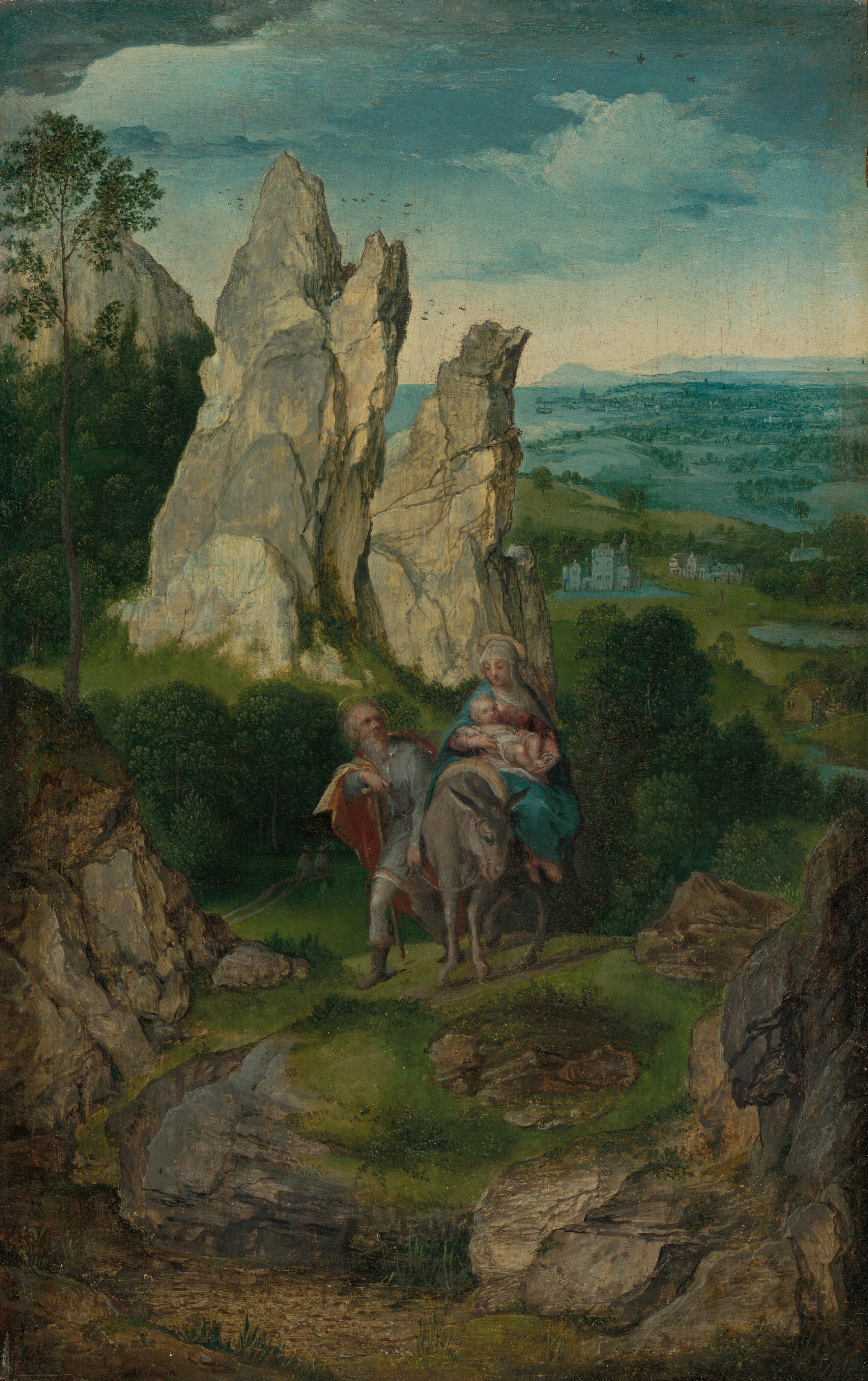 This painting depicts a rocky pass with a man, woman, and child moving up a hill towards us. In the background is a rugged rock formation rising towards the top left, leading down to a horizon with green fields and distant blue hills. In the center of the painting, a woman in a red gown and blue cloak holds a child wrapped in a white cloth. The woman rides a donkey, and a man walking left next to her on the left holds the reins. The man wears a gray garment under an orange cloak, and he walks with a crutch in one hand. Both the man and woman have halos around their heads. The hill they are on is covered in lush green grass, and green trees fill the areas between the rock formations. Far away, small white buildings are visible below. The sky above the scene is white along the horizon but blue at the top of the painting, with a few faint clouds drifting by.