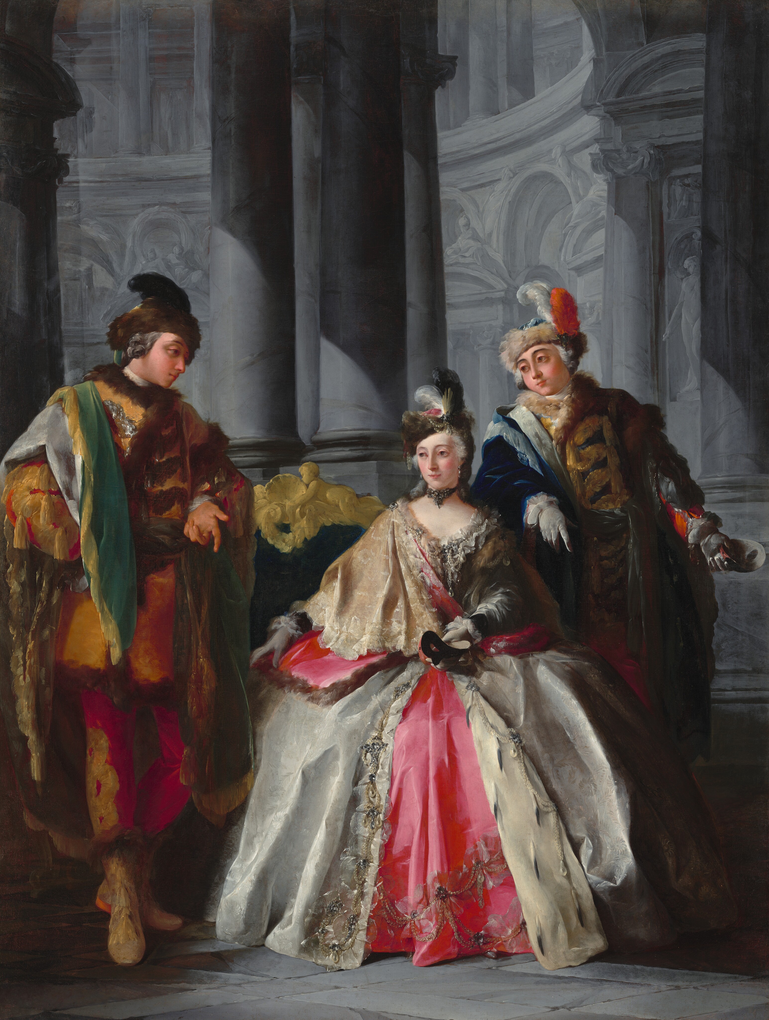 In this painting, there are three individuals dressed in elaborate outfits inside a gray, columned interior. The central person is a woman seated on a green couch with ornate golden detailing. She has fair skin, rosy cheeks, and white hair styled upward under a dark brown cap covered with white gems, pearls, and feathers in white, pink, and brown. She wears a luxurious gown with a pink and silver color scheme, adorned with intricate patterns including cream lace designs, gems, and pearls near the neckline and bottom of the dress. She has white gloves on her hands, one of which holds a black mask. Her companions stand on either side of her, both with light skin and curled gray hair. The man on the left wears a richly colored outfit with gold, brown, and green accents and a matching brown hat. The man on the right is dressed in blue, red, and gold, with a fur-collared coat and a blue feathered hat. The background is an architectural setting with tall columns and intricate stonework, all in shades of gray.