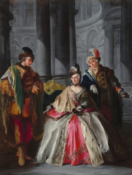 In this painting, there are three individuals dressed in elaborate outfits inside a gray, columned interior. The central person is a woman seated on a green couch with ornate golden detailing. She has fair skin, rosy cheeks, and white hair styled upward under a dark brown cap covered with white gems, pearls, and feathers in white, pink, and brown. She wears a luxurious gown with a pink and silver color scheme, adorned with intricate patterns including cream lace designs, gems, and pearls near the neckline and bottom of the dress. She has white gloves on her hands, one of which holds a black mask. Her companions stand on either side of her, both with light skin and curled gray hair. The man on the left wears a richly colored outfit with gold, brown, and green accents and a matching brown hat. The man on the right is dressed in blue, red, and gold, with a fur-collared coat and a blue feathered hat. The background is an architectural setting with tall columns and intricate stonework, all in shades of gray.