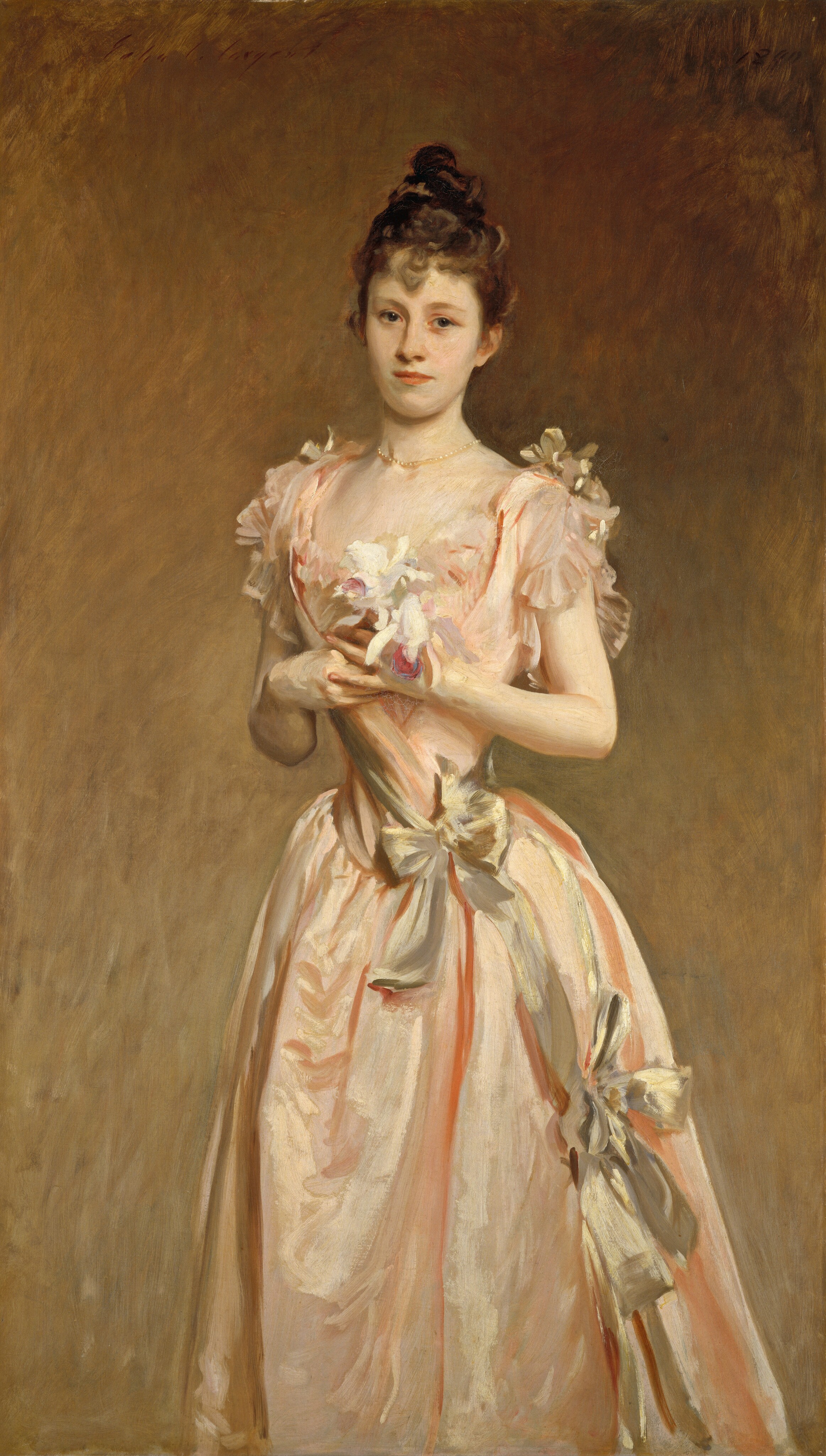 Shown from about the knees up, a young woman with pale skin, wearing a long, flowing, peachy-pink satin dress, looks at us in this vertical portrait painting. Her shoulders are slightly angled to our left, and she gazes out with dark gray eyes set in an oval face. She has a long, narrow nose, smooth skin, and her pink lips are closed. Her light brown hair is pulled up and twisted into a loose bun high on her head, and a curl hangs down the center of her forehead. A pearl necklace rests at the base of her neck. Her dress has a low, sweeping neckline and short, fluttering sleeves. The peach of the fabric almost blends in with the color of her skin in some areas. The dress has a tightly fitted bodice around a notably narrow waist, which is tied with a gold sash and bow. A gold ribbon from the bow on the side of her waist leads to another farther down her skirt, near her left knee, to our right. More gold bows are tied atop her shoulders. The deep folds of her peach skirt are shaded with darker coral streaks. The two orchids she holds at her chest are mostly white but they have a couple of pale, lavender-purple petals, and each has a deep magenta-pink tongue. The background lightens from coppery brown along the top to a golden tan along the bottom. Some areas of the portrait are loosely painted, especially in the skirt and background. The artist signed the painting in the upper left corner, “John S. Sargent” and dated it in the upper right, “1890.”