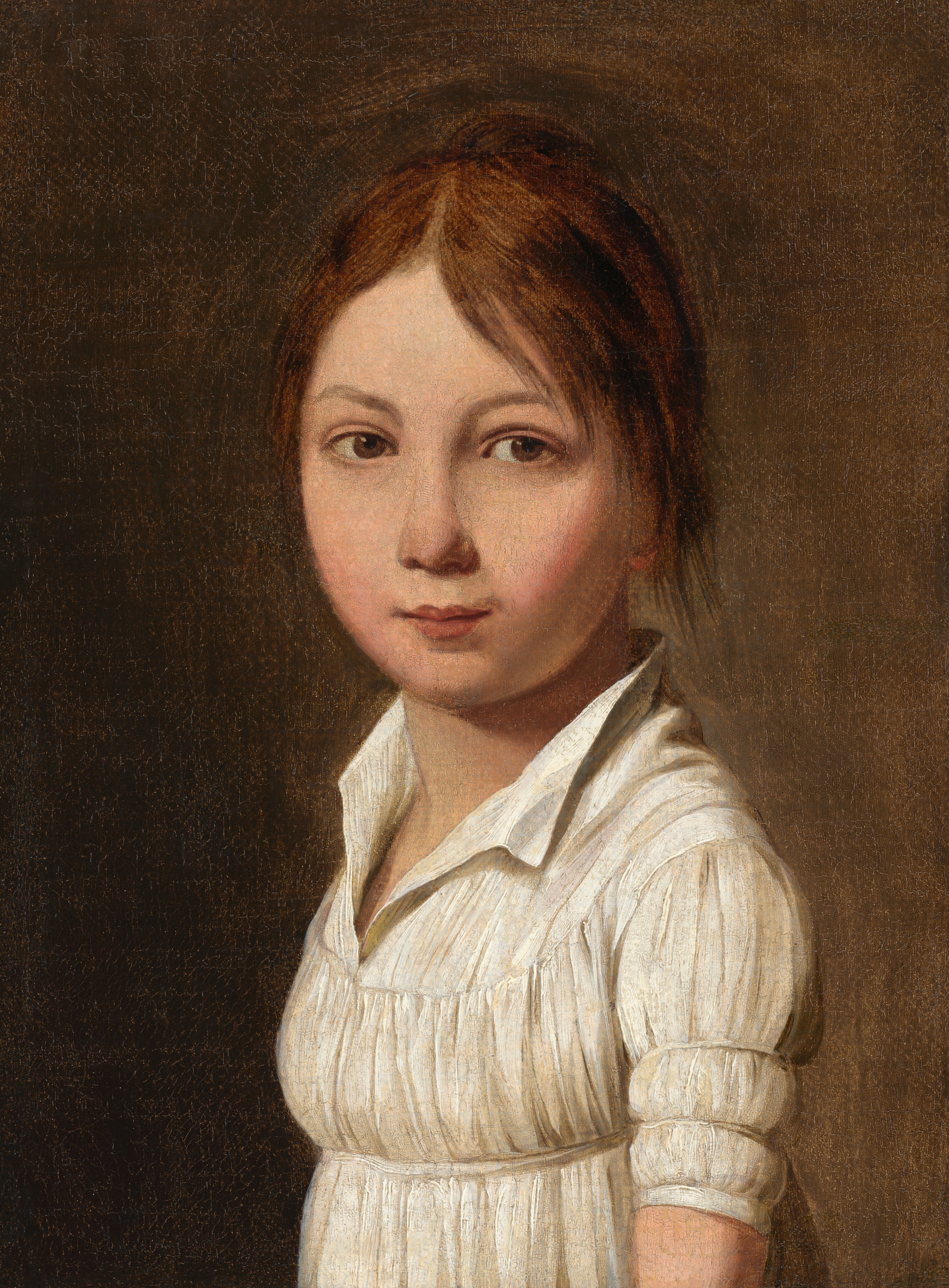 The image displays a young person from the waist up, facing the viewer. They have a round face with soft features, light brown eyes, and a small mouth. Their brown hair is parted in the middle and falls smoothly to the sides. They wear a white garment with a high collar and puffed sleeves that end just above the elbows, made of a light, textured material. The background is a plain brownish tone. No jewelry or objects are visible.