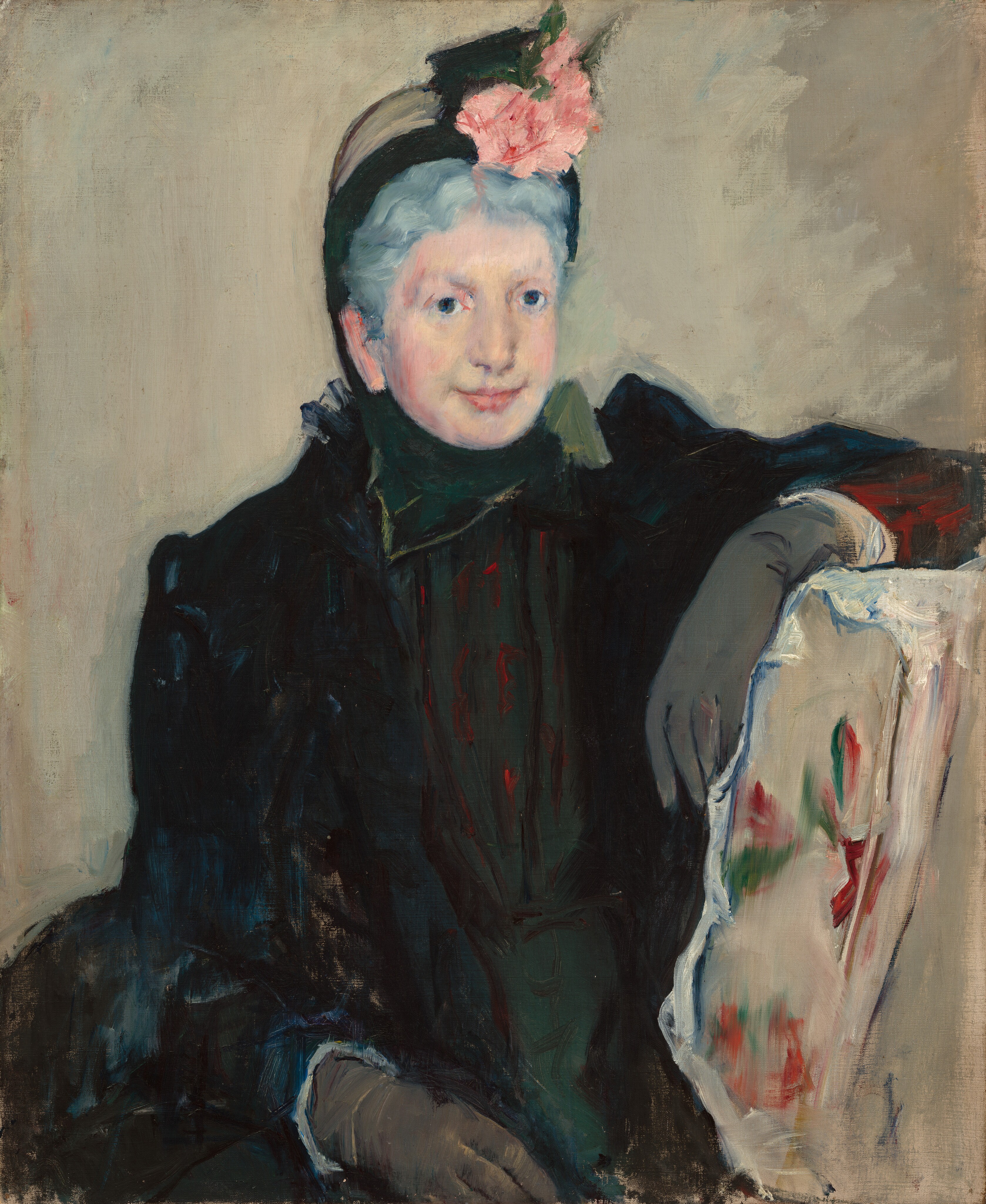 Shown from the lap up, an older woman with pale, slightly sagging skin and frosty gray hair sits facing us in this loosely painted vertical portrait. Her body is angled very slightly to our right, and she rests one elbow across the back of the chair in which she sits. She has a round face with large, dark blue eyes, and she smiles. Her gray hair is pulled back under a black hat, which is topped with pale pink flowers. She wears a black coat over a high-necked, hunter-green garment and nickel-gray gloves. The chair is painted loosely with a red and green floral pattern against a white background, and the space behind the woman is parchment white.