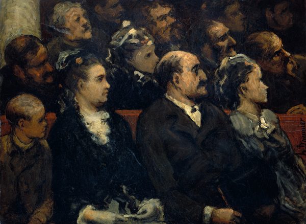This painting shows a crowd of seated people facing the right, mostly seen from the waist up. The people are seated in rows of red seats, and closest to us is a row of four people. In the bottom left corner is a child with very short dark hair and a dark brown coat over a white collar. To the right is a woman with dark hair in an updo and adorned with what looks like a blue ribbon, and she wears a dark dress with a white ruffled collar and white cuffs. Next to her is a man with a mustache and balding head, dressed in a formal dark suit. To the far right is another woman with a light blue-gray dress or coat and short, light-colored hair with a bow or ribbon. More people are partially visible in the rows behind, but their features become increasingly soft and blurred towards the background. All of the people appear to have light skin, although some of the people on the left side and in the back appear to be in shadow, making it ambiguous.