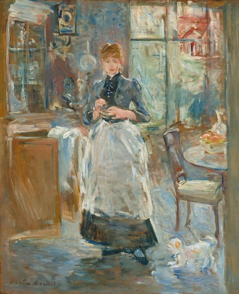 A young woman with pale, peach skin wearing a white apron over an ankle-length navy-blue dress stands in a dining room in this vertical painting. The painting is created using loose brushstrokes throughout. The woman stands facing and looking out at us. Her auburn-brown hair is pulled up into a bun, and bangs sweep across her forehead. Her eyebrows are slightly raised, her deep pink lips are closed in the hint of a smile, and she holds her hands at her chest. Some details throughout the painting are indistinct because of the loose painting style but she might hold a mixing bowl. The high-necked bodice of the dress has buttons down the front, and the apron falls to mid-shin. A tall curio cabinet fills the space to our left and brushes the top edge of the canvas. It seems to be filled with white or silver serving pieces, and a white cloth is draped over one of the open cabinet doors below. A clock hangs on a wall over an oil lamp between the woman and curio cabinet. Light pours in through a tall window or French doors behind the woman to our right. Roughly painted forms suggest a house and landscape beyond. One chair is pulled up to a round table that is cut off by the right edge of the canvas. A decanter, perhaps glass, and bowl of peach and rose-colored fruit sit on the table. A small white dog with tan spots scampers at the woman’s feet near the chair. The artist signed the painting in brown in the lower left corner: “Berthe Morisot.”