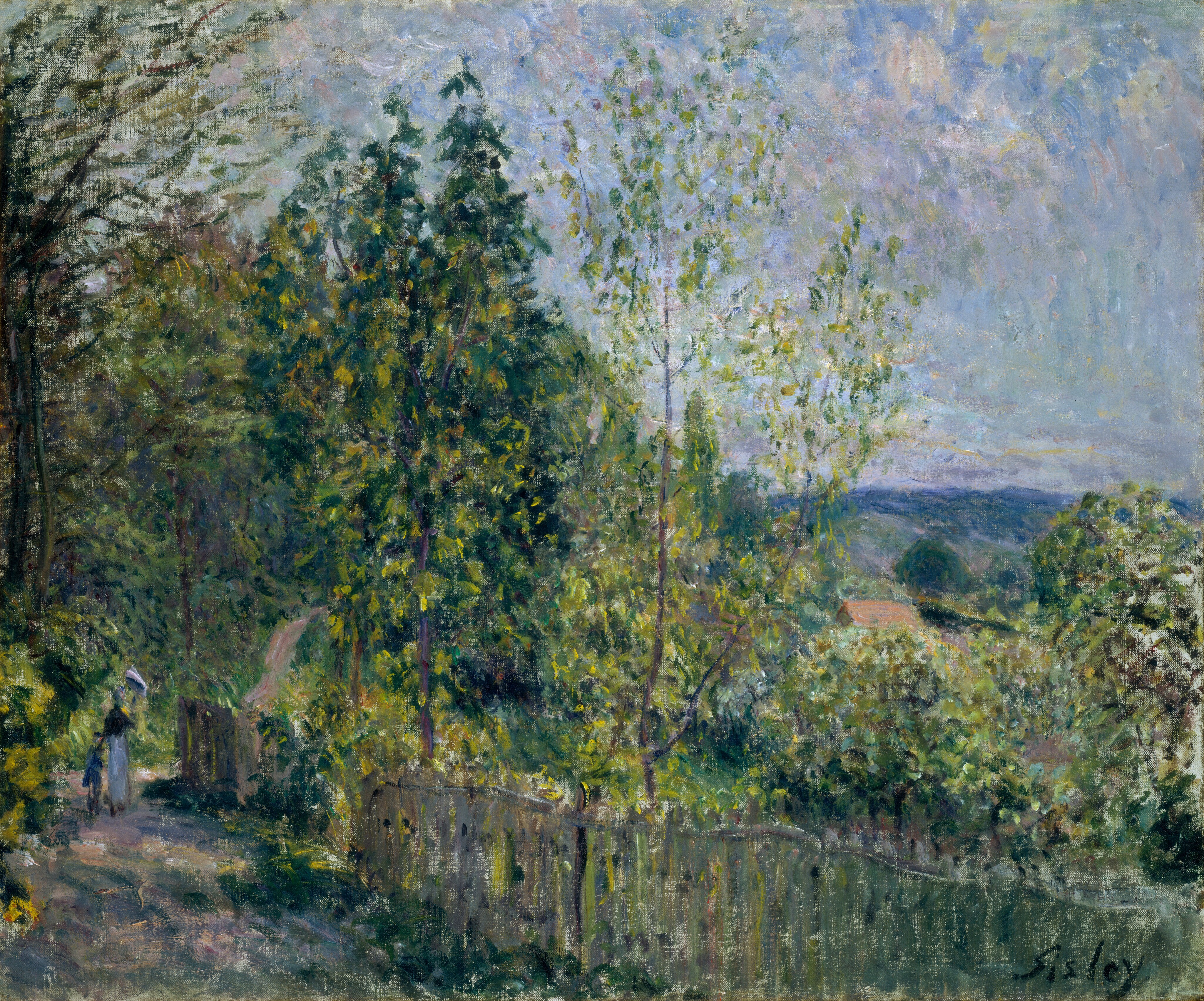 This painting depicts a scene where a winding path on the bottom left leads into a wooded area. Tall green trees occupy the left side of the painting, while on the right a small gap shows a hilly, dark blue horizon line with more green foliage and the red roof of a building. The sky above is light blue with dots of white and lilac purple. Across the bottom of the painting, a wooden fence lines a light brown path that leads through the woods. Near the bottom left corner, small strokes of paint suggest two people walking along the path away from us, one adult and one child. The color palette is predominantly green with hints of light brown, along with soft blues and purples in the sky. The brushstrokes are loose and impressionistic, with paint applied in short, overlapping lines and dots.
