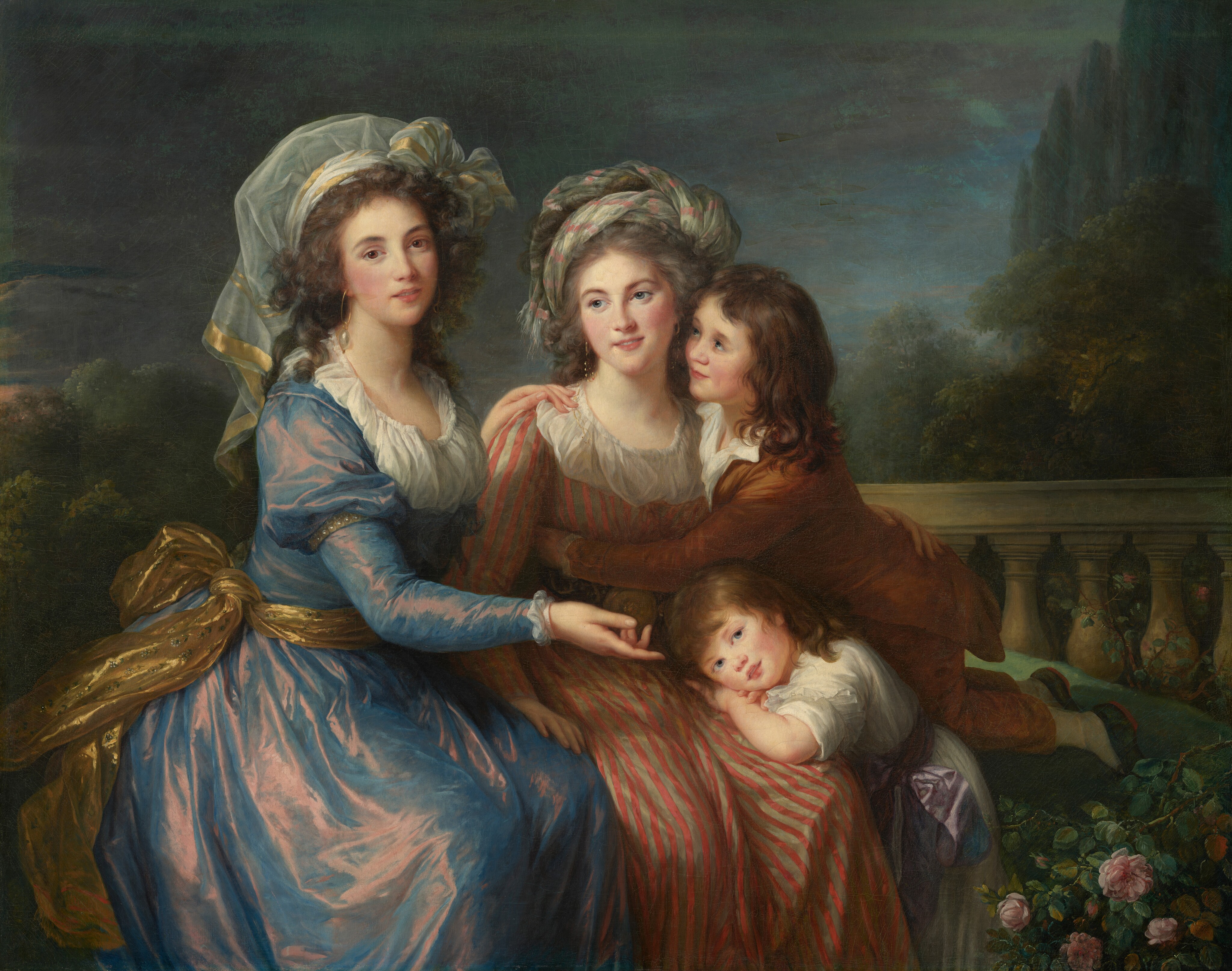 Shown from the shins up, two elegantly dressed women and two young boys, all with light skin, sit together on a bench in front of a stone balustrade with a forest landscape beyond in this horizontal portrait painting. The people are brightly lit from our left but the darkened sky suggests dusk. The boys lean onto the woman at the center of the composition, and the second woman sits to her right, our left. All of the people have pale skin, rosy cheeks, delicate noses, and their pink lips all turn up in slight smiles. The woman on our left sits with her body angled toward her friend but she turns her face to look at us with brown eyes under curving brows. Her wavy, flint-gray hair is loosely bound up so it frames the sides of her face and curls over her shoulders. Her swirling, white head covering is edged in gold and tied in a bow over her left ear, on our right. Her long-sleeved dress has a tight-fitting bodice and a low, scooped neckline lined with pleated white fabric. Her dress shimmers from sapphire blue to dusky pink, suggesting it is iridescent taffeta. Large pearls hang off the end of round, gold, hoop earrings, and a glimmering gold sash is tied around her waist. She sits with her left hand resting on her friend’s right shoulder, closer to her, and she gestures toward one of the young boys leaning on the friend’s lap with her other hand. The second woman sits with her body facing us, and she looks off to our left with gray-blue eyes. Her silvery gray, upswept hair is covered with a long piece of white fabric with pink stripes, twisted loosely into a turban-like head covering. She wears dangling gold earrings, and her dress is striped with parchment white and rust red. Her right hand, on our left, rests on her friend’s knee, and her other arm is wrapped around the older boy. He kneels on the bench and leans forward, wrapping the arm we can see around her torso. His face near hers, he looks up at her from under his lashes. A dimple marks the flushed cheek we can see. His chestnut-brown hair falls around his shoulders, and he wears a gingerbread-brown suit. The smaller and younger of the two boys rests his head on his crossed hands on her thigh, and looks out at us. He wears a white garment with a lilac-purple sash tied in a bow around his waist. There is a pale pink rosebush in the lower right corner of the painting, near the kneeling boy’s foot. The landscape beyond the balustrade is filled with dark green trees against a slate-blue sky. The painting is created with blended brushstrokes, giving it a soft look.