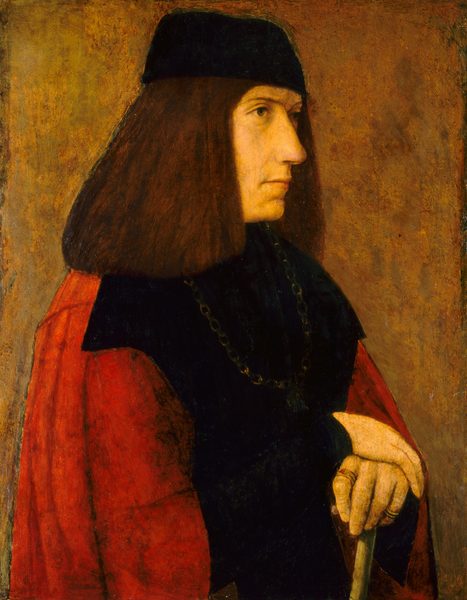 This painting shows a man seen from the waist up, facing to the right with his hands resting on a cane. He has pale, yellow-toned skin, a straight nose, thin eyebrows, and thin, straight lips. His hair is dark brown and shoulder-length, and on top of his head is a black cap. He is dressed in dark clothing with a high neckline, a chain necklace across his chest, and a red garment over his shoulders. He wears rings on his fingers. The background is a yellow-brown color with visible brushstrokes.