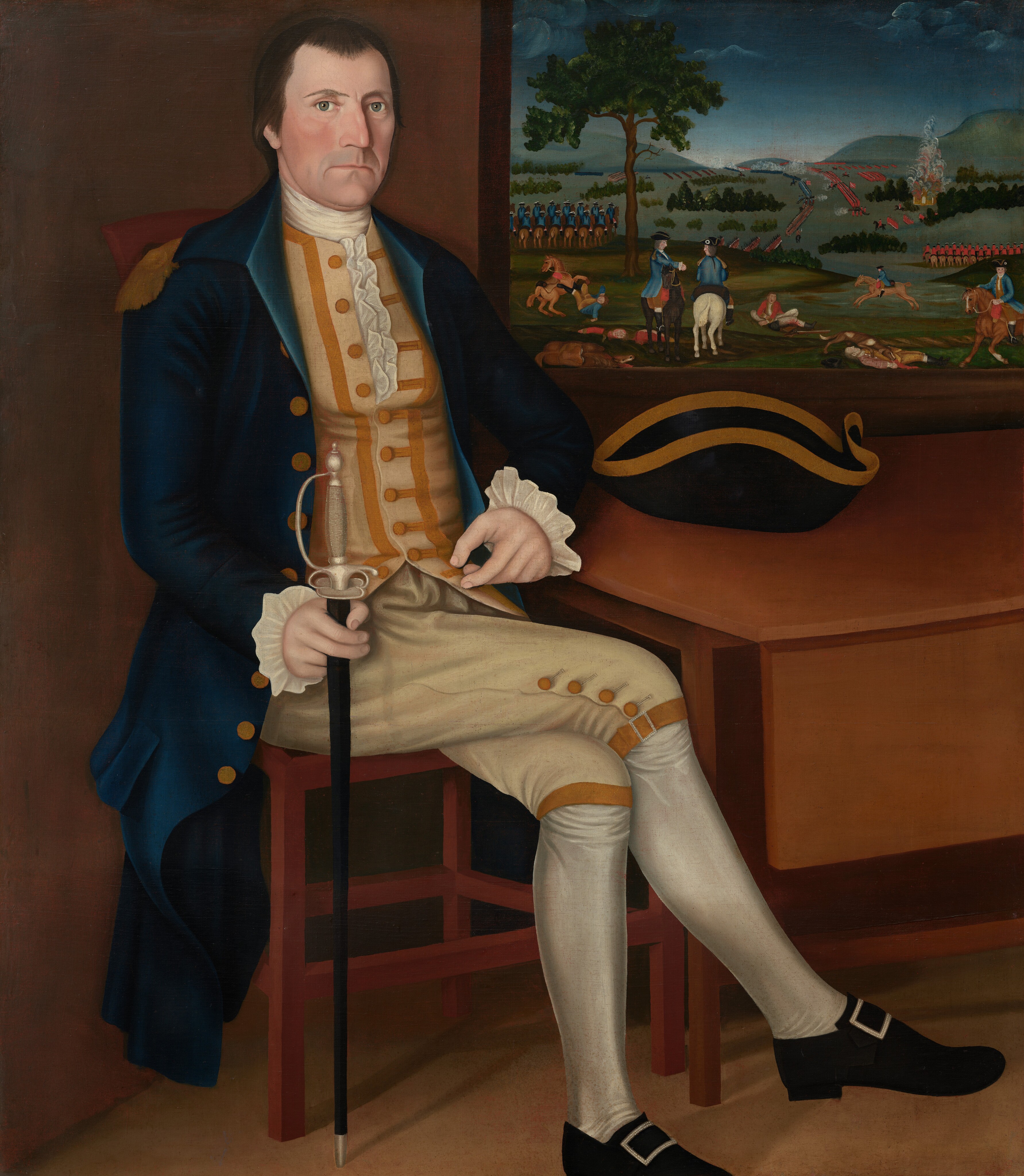 This painting shows a man seated, with his full body visible. His body is slightly turned to the right, but he looks out at us, one hand resting on his knee and the other holding a sword upright. The man has a serious expression, light skin, a square jawline, and high cheekbones. His hair is dark and styled neatly. He is wearing formal attire consisting of a blue coat with gold buttons, a yellow waistcoat with white frilled cuffs, and beige breeches with button details. His stockings are white, and his shoes are black with rectangular buckles. Nearby, on a table, rests a black tricorn hat with gold trim. The background features a window or painting depicting lines of soldiers, horses, and trees under a dark blue sky.