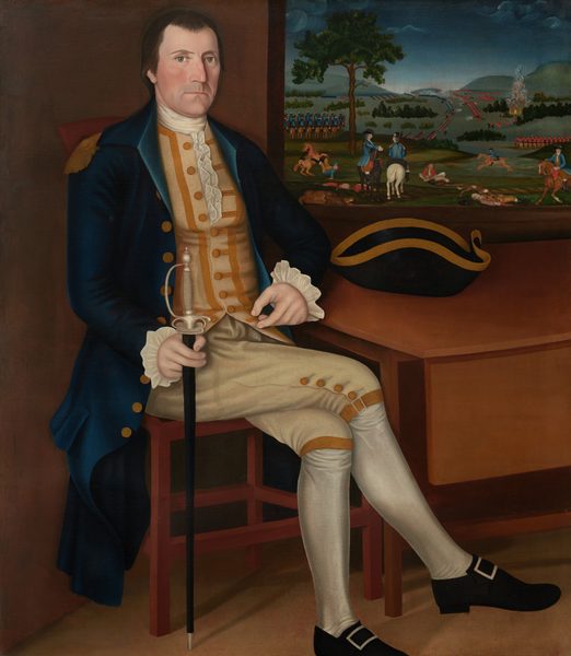 This painting shows a man seated, with his full body visible. His body is slightly turned to the right, but he looks out at us, one hand resting on his knee and the other holding a sword upright. The man has a serious expression, light skin, a square jawline, and high cheekbones. His hair is dark and styled neatly. He is wearing formal attire consisting of a blue coat with gold buttons, a yellow waistcoat with white frilled cuffs, and beige breeches with button details. His stockings are white, and his shoes are black with rectangular buckles. Nearby, on a table, rests a black tricorn hat with gold trim. The background features a window or painting depicting lines of soldiers, horses, and trees under a dark blue sky.