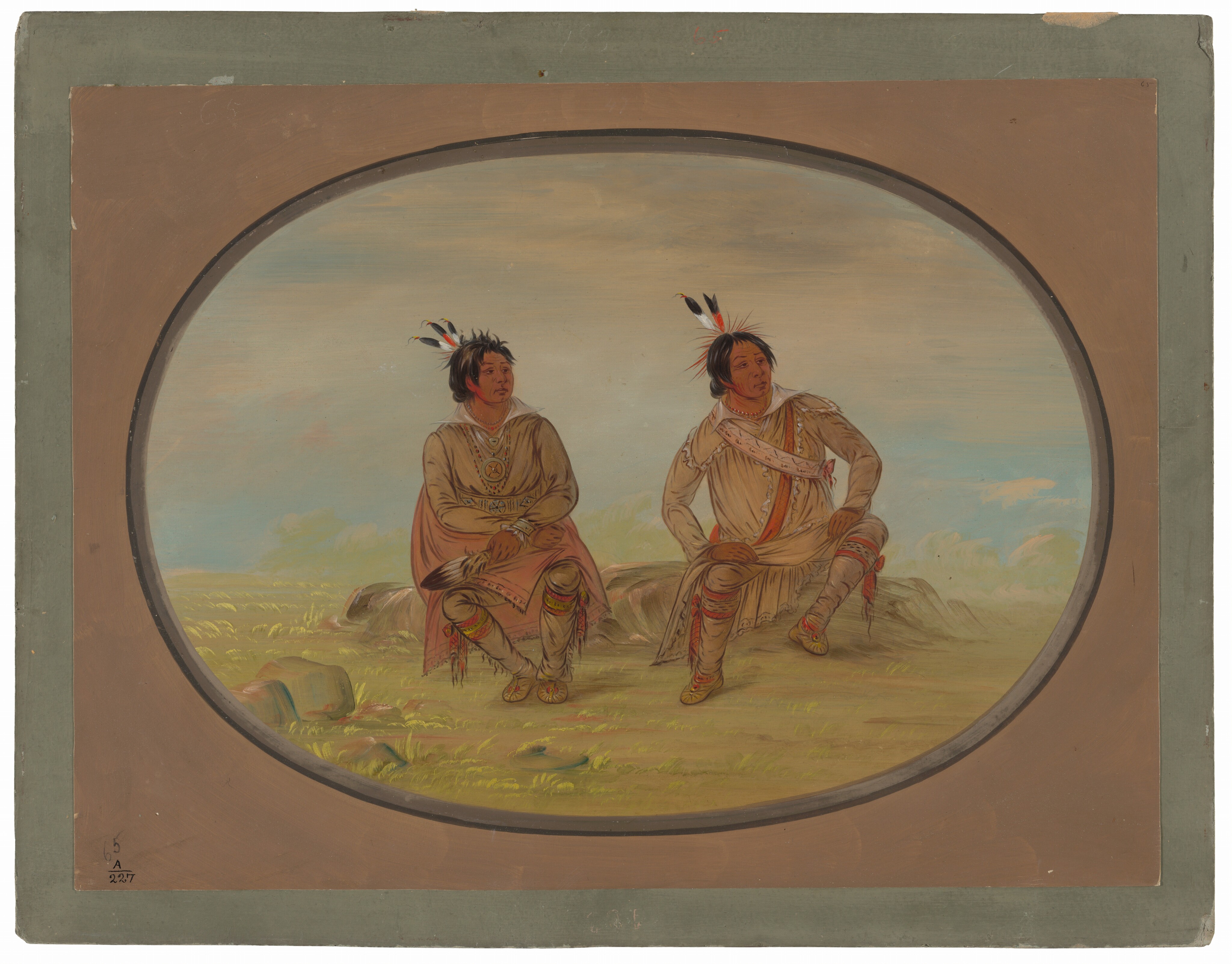 The image includes two seated figures, both shown from the knees up. Each person is seated with their legs bent and feet resting on the ground. The individual on the left has dark hair with feathers and wears a long garment with a pattern across the chest and over the shoulders. Their garment reaches the knees, revealing moccasin-style footwear. This person holds an object in their hand, which appears to be a feather fan or similar item. The figure on the right also has dark hair with feathers and wears a long-sleeve top with a decorative sash, knee-length leggings, and moccasins. The background shows an open landscape with green plains, rocks, and a cloudy sky, suggesting an outdoor setting. The image is enclosed within an oval frame.