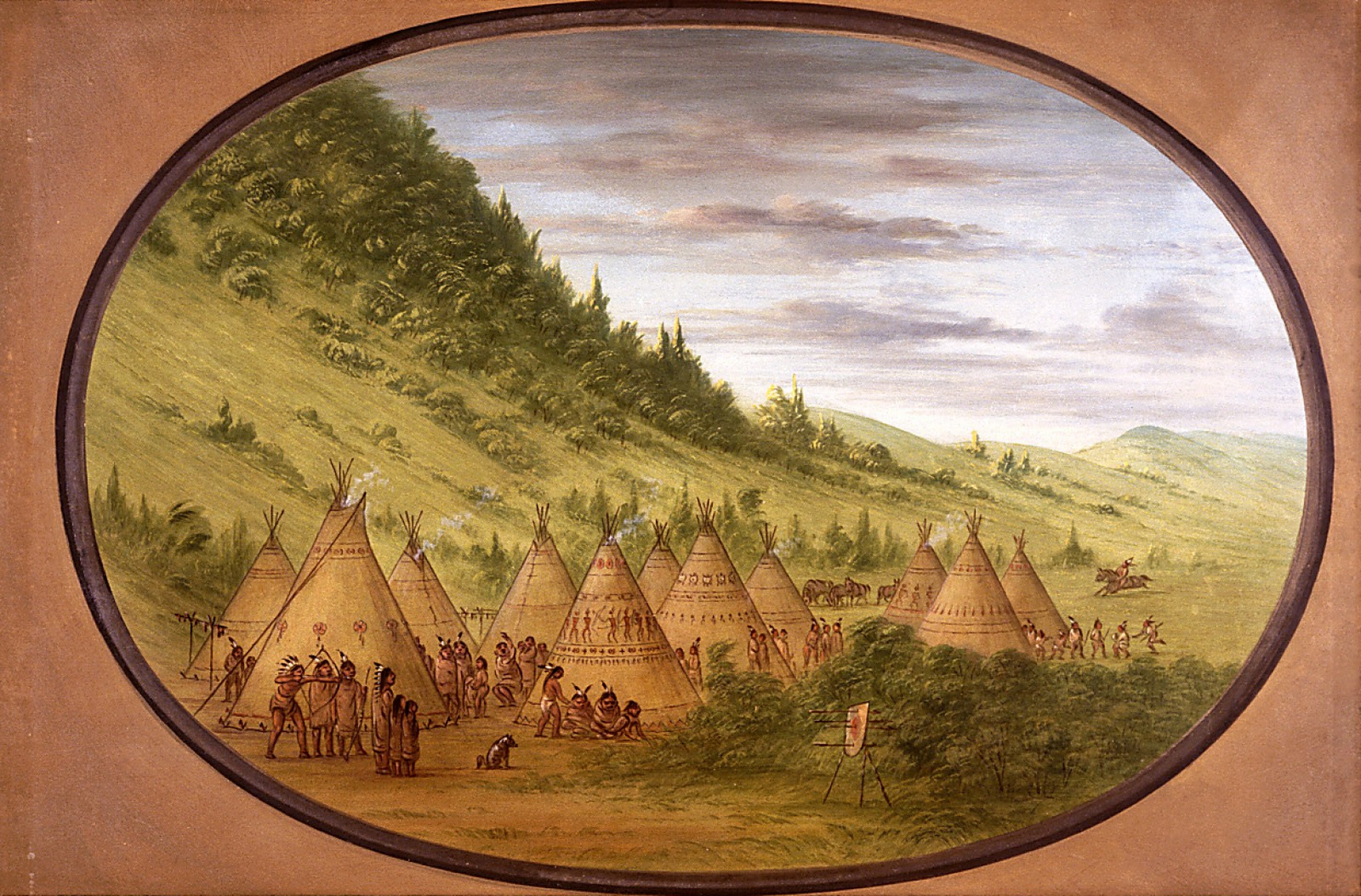 The image shows a Native American camp from an elevated viewpoint. The scene includes tipis with symbols and people engaged in various activities. The setting features distant hills under a cloudy sky, with soft transitions between land and sky. The brushstrokes are delicate and precise, creating a realistic landscape. The color palette is dominated by earthy tones, with greens for hills and browns for tipis and earth, while the sky is a blend of grays and blues. Figures on horseback in the distance add movement to the scene. The painting is bordered by an oval frame.