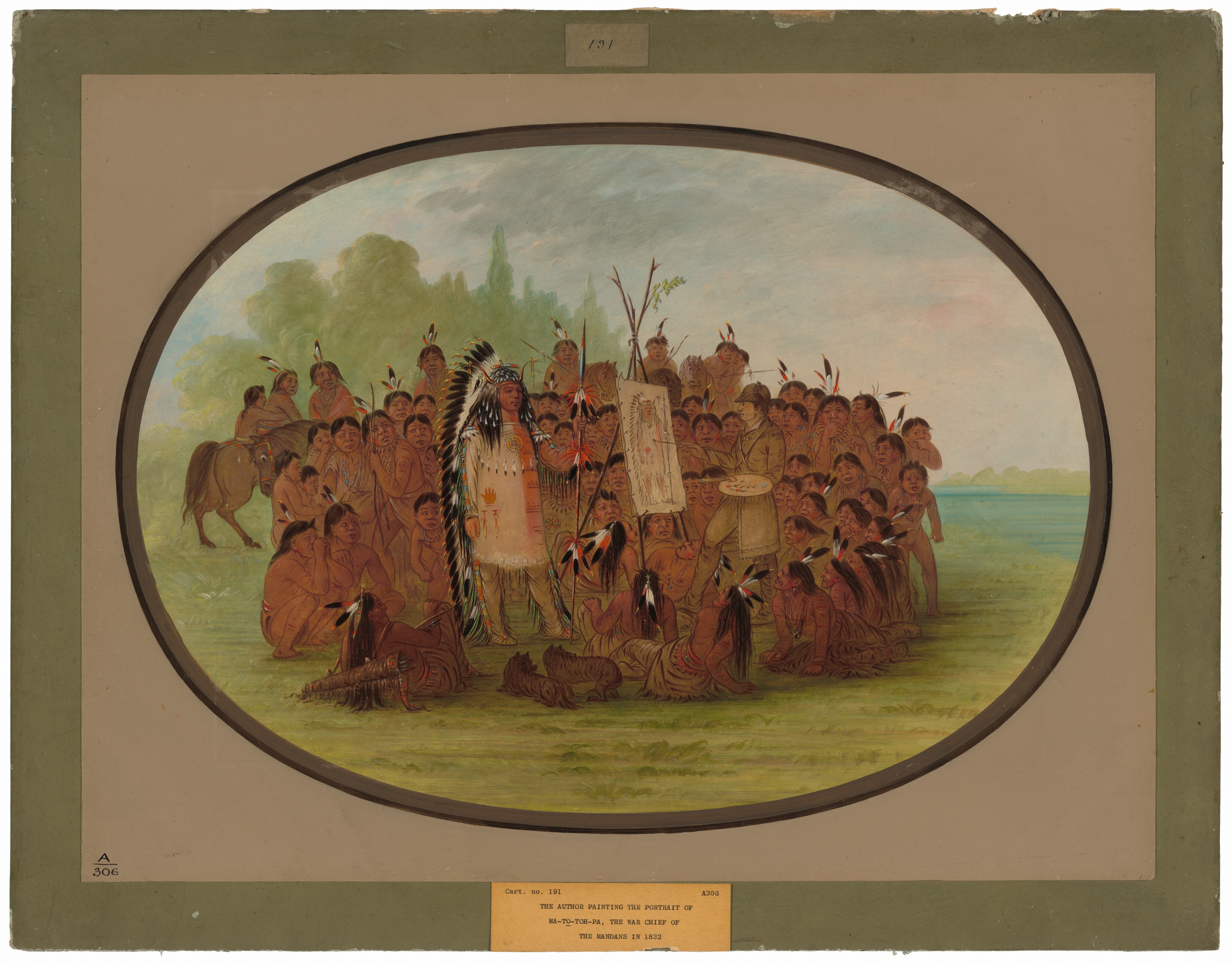 This is a painting of a large group of people outdoors. In the center, two people face each other, one painting a portrait of the other.  Every person in the image except the painter has reddish-brown skin; the painter has pale, yellowish skin. To the left of center, the person being painted stands tall, wearing intricately decorated clothing. They wear a long, tan garment painted with several designs, such as feathers, a handprint, and a colorful circle. The front of the garment has a wide red stripe running down it. On their legs, they wear tan pants with long black tassels on the side. Down the sides of the long garment and the pants are bright squares of teal, yellow, and red. On top of their long black hair, this person wears a long headdress made of white and black feathers that travel from their head all the way to the ground. They also wear thin red horns on their head, and they hold a tall staff or spear decorated with feathers and red fringe. On the right, the person with pale skin paints a depiction of the staff-wielder on a tan canvas. This person holds a palette and several brushes. They wear a simple brown tunic, brown pants, a white collar, and a brown hat. Surrounding these two people is a large crowd of other people kneeling, sitting, standing, or riding on horseback. These onlookers have a range of expressions, and they wear a variety of clothes. Most of them wear tan garments, and some have necklaces around their necks or red paint on their arms. Many of them have feathers in their black hair. Close to us, some small dogs sit among the seated onlookers. The group is positioned on green, grassy ground, with tall trees in the distance. The sky overhead is blue-gray, and there appears to be a blue river off to the right. The entire composition is framed within a dark oval border, outside of which is plain, off-white paper.