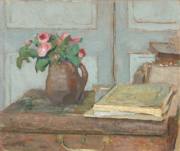 This painting shows a brown jug filled with pink roses and green leaves on a brown surface that looks like a suitcase on its side. To the right of the jug are some stacked books, which are a light green color. The background is a light blue paneled wall or door, and there appear to be some open boxes behind the suitcase on the right side. The brushstrokes are thick and visible.
