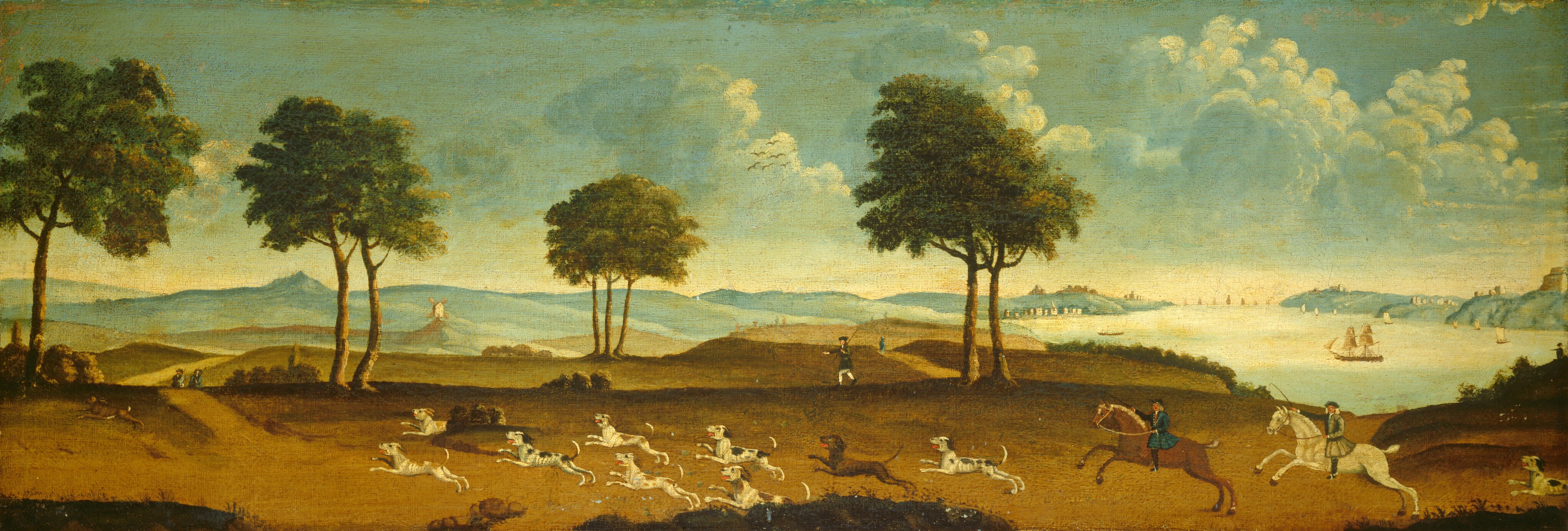 Two pale-skinned horsemen and a pack of ten dogs race across a brown ridge overlooking a river in this long, horizontal painting. The horsemen turn to face us as they and the dogs chase an unidentifiable brown animal from right to left. The front rider wears a peacock-blue coat and black hat over gray hair, while the following rider wears a pewter-gray coat and darker hat over white hair. Most of the dogs have white coats dappled with tan or black spots and one dog is chocolate brown. A man walks along the ridge beyond the dogs and two more men further to the left are shown from the waist up beyond the crest of the ridge. Tall, leafy green trees are placed in four groupings across the left two-thirds of the landscape. The landscape beyond the trees transitions to paler brown and then shades of slate blue. A solitary windmill perches on a hill on the far left and faces gently sloping blue mountains rising in the far distance. Those blue mountains slope down to a wide, pearl-white river tinged with teal blue on the right. Tiny ships and sailboats travel the river, and buildings line the riverbank and cluster on the hills above. A muted blue-green sky filled with puffy white clouds with flax yellow highlights spans the top half of the scene.