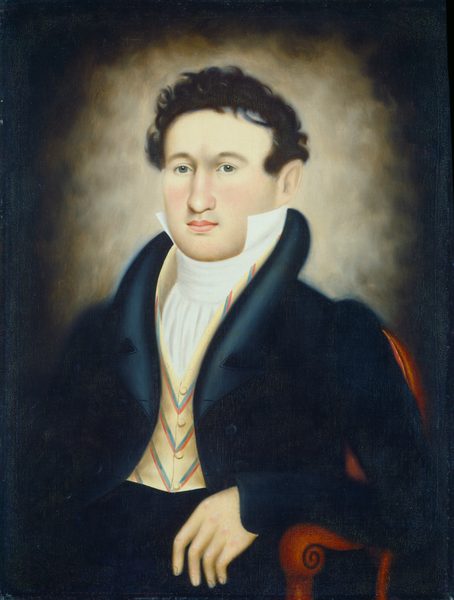 The image shows the upper half of a man's body. He is seated, resting his right arm on the arm of a chair. The man has fair skin, dark curly hair, and a composed expression. He is dressed in formal attire, including a white shirt, vest with red, white, and green or blue stripes, and a dark jacket. The background is a blend of browns.
