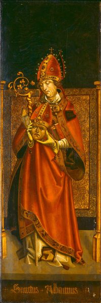 The image depicts a figure identified as "Sanctus Albanus." The individual is standing upright and adorned in ecclesiastical attire, including a bishop's mitre with jewels and a cross at the top, a red robe with gold trimmings, and a white vestment peeking out. The figure's face is serene, framed by curly brown hair. One hand holds a crosier, while the other cradles a mitred head. The background is dark, contrasting with the opulent gold and red attire. The intricate design work is visible on the clothing and a golden panel behind the figure. The base of the panel bears the text "Sanctus Albanus" in decorative lettering.