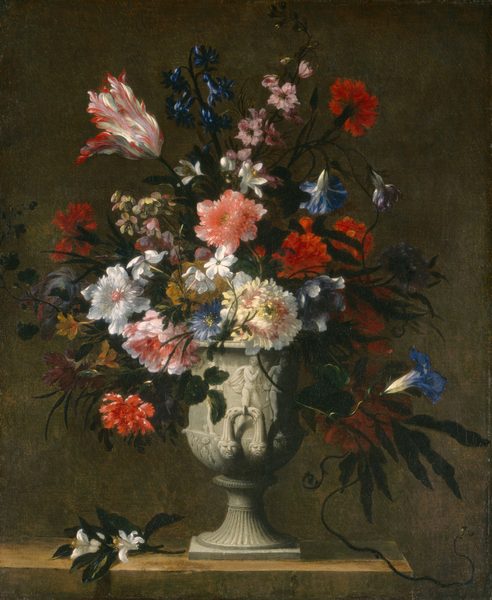 This painting shows a large white vase filled with a dense assortment of vibrant flowers. The bouquet includes flowers in shades of deep red, bright pink, white, and dark blue, with a few yellow flowers in the back. The leaves and stems of the flowers are such a dark green that they appear almost black. The vase is carved with some images of nude people, with some geometric patterns towards the base. It rests on a wooden table, with some flowers spilling over its edge onto the table. The background is dark brown, and the flowers cast dark shadows on the vase and table.