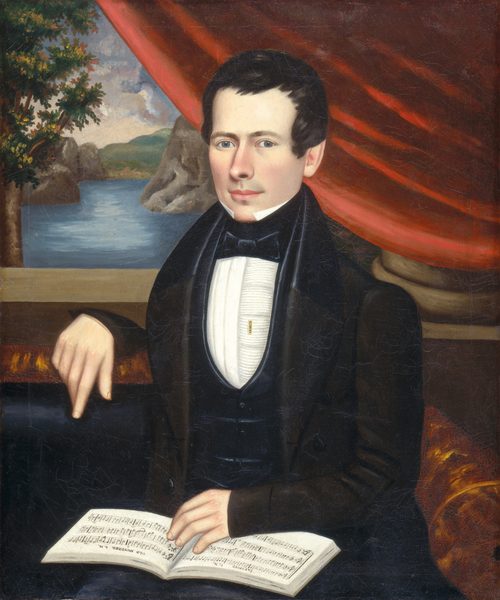 The image shows a man sitting in a portrait pose. He is wearing a dark suit with a white shirt and a black bow tie. His hair is styled neatly, and he has a fair complexion with an attentive expression. He is holding an open book of sheet music. The background includes a red curtain and a landscape with a river or lake, rocks, and greenery.