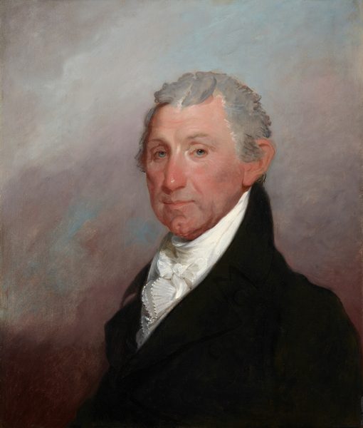 This painting depicts a man from the waist up. He is looking at us, his body turned slightly to the left. The man has fair skin, blue eyes, short gray wavy hair, a cleft chin, and prominent ears. He is dressed in a black coat with a high collar and a white cravat. The background is a blend of muted colors in brown, pale pink, and gray hues.