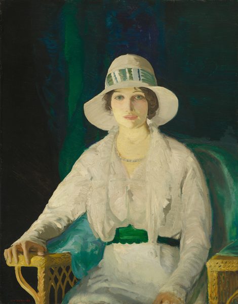 This painting is a portrait of a seated woman shown from the knees upwards. She is seated in a woven yellow armchair, with her right arm resting on one arm of the chair, while her left hand rests on her lap. The chair is slightly turned to the left, but she looks directly at us. She has pale skin with slightly pink cheeks, round blue-green eyes, thin brown eyebrows, and pink lips set in a neutral expression. Her hair is dark brown and styled in soft waves, visible beneath a wide-brimmed cream hat adorned with a striped green-and-white band. The woman wears a white dress with a green belt or sash around the waist and a pearl necklace. A green cloth appears to be draped on the chair beneath her, and the background is a deep blend of green, dark blue, and black shades, similar to a heavy draped curtain. The brushstrokes in the painting are thick and visible.